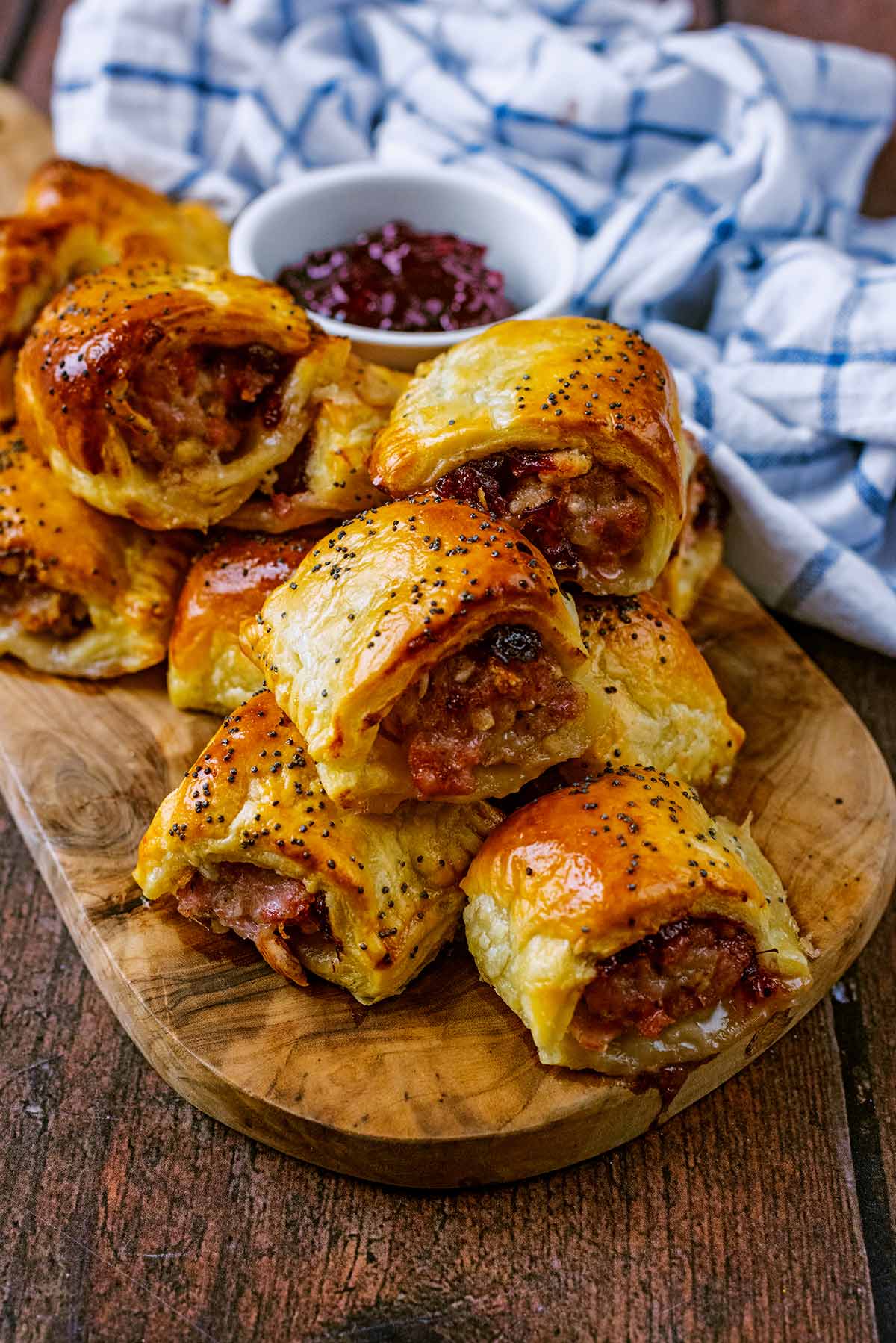 A pile of sausage rolls on a wooden serving board.