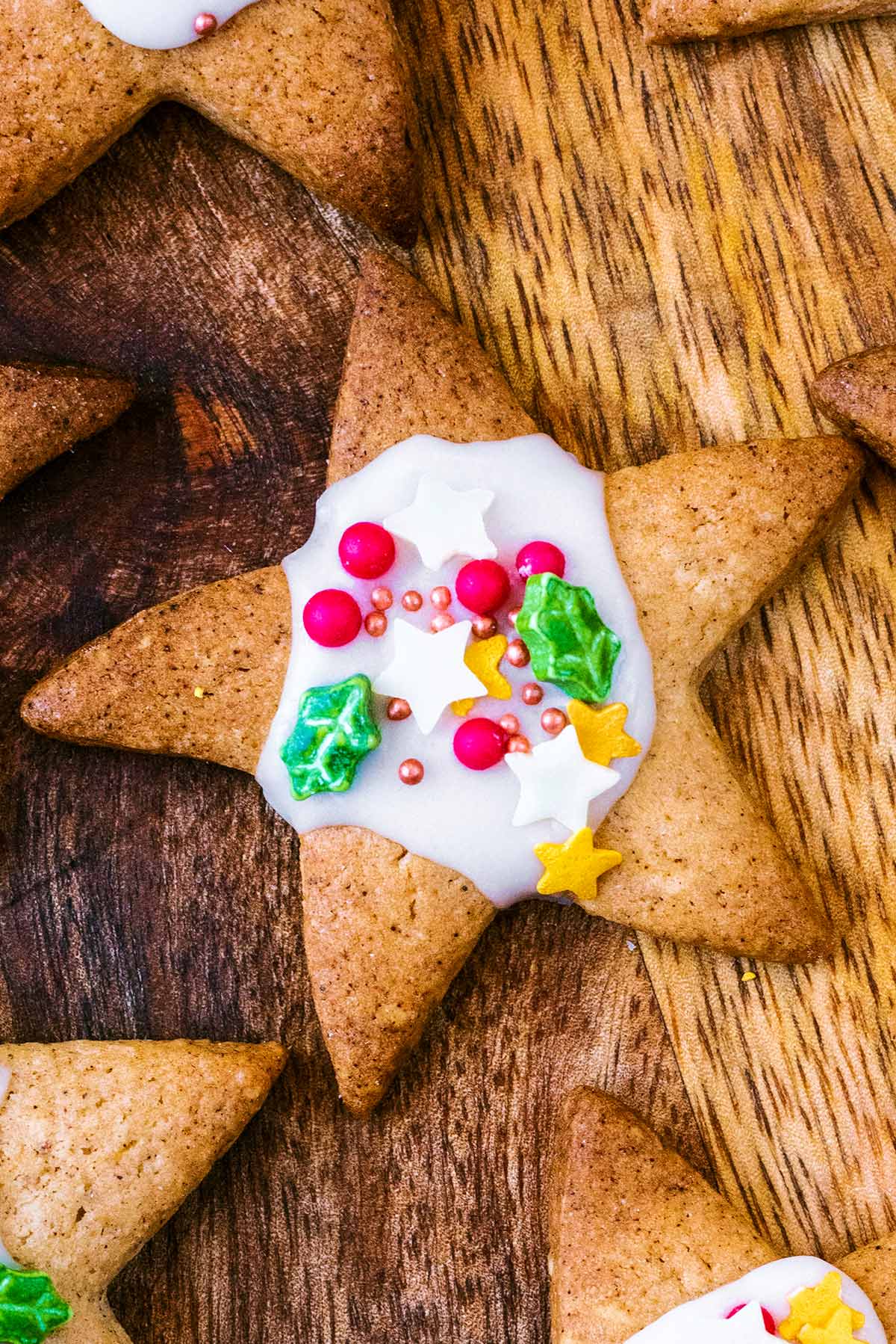 A star shaped biscuit topped with white icing and some festive sugar sprinkles.