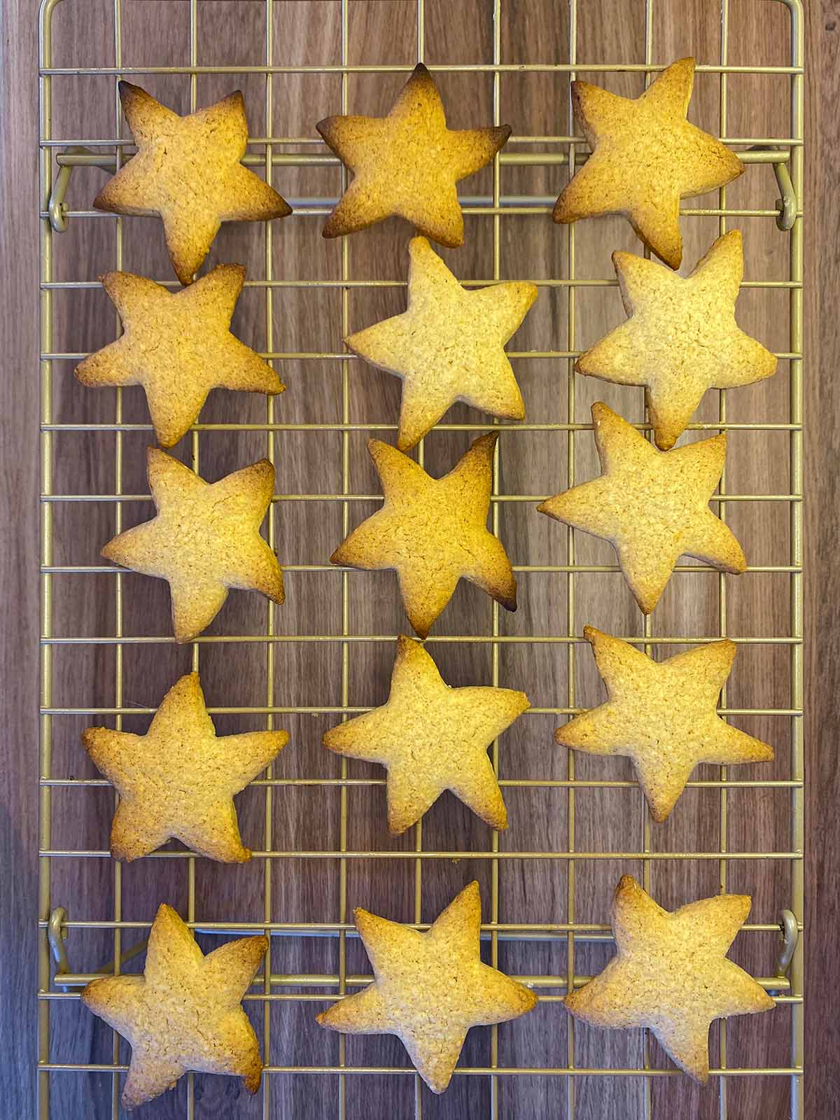 Cooked star shaped biscuits cooling on a wire rack.