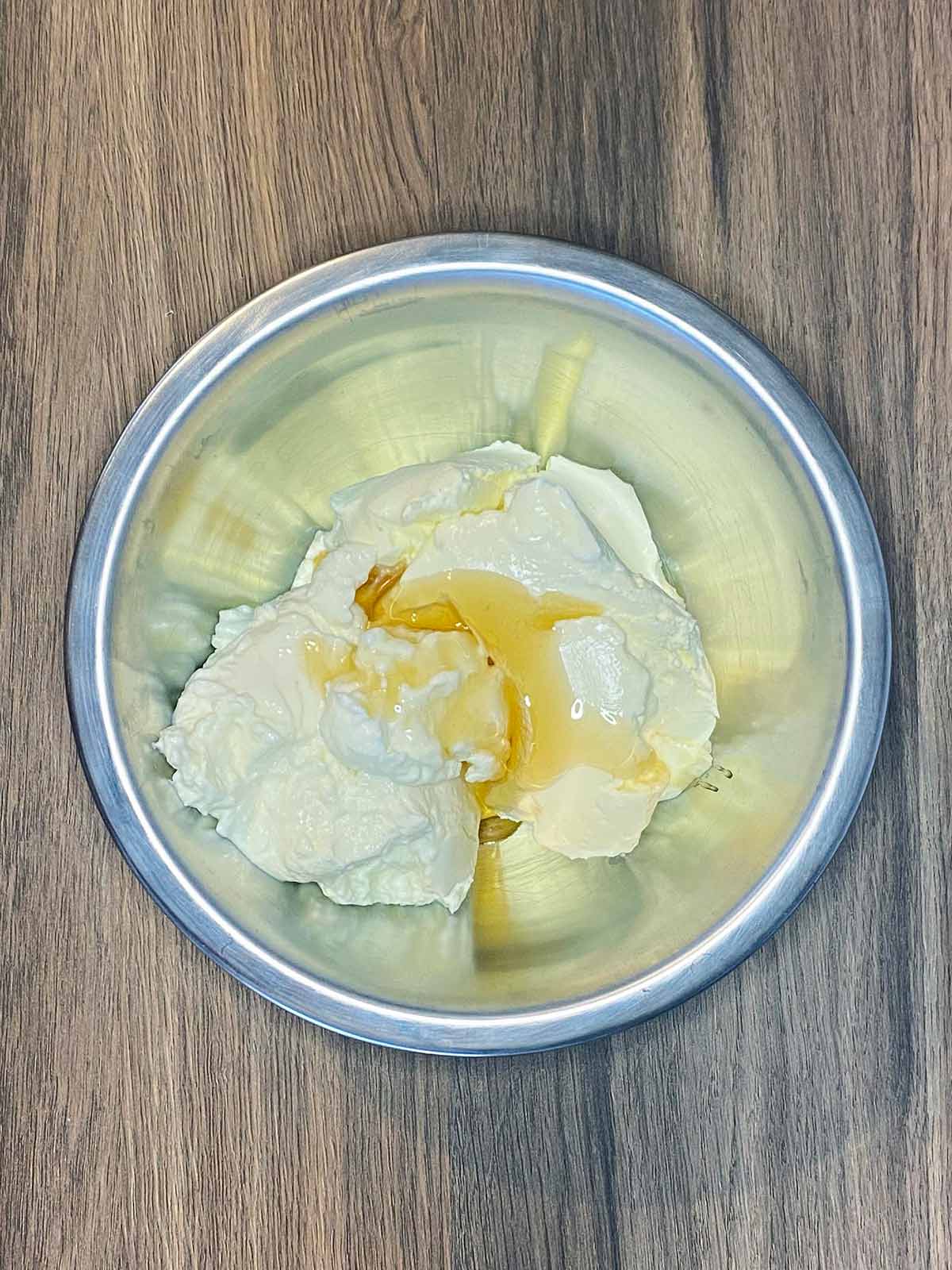 A mixing bowl containing cream cheese, Greek yogurt and vanilla.
