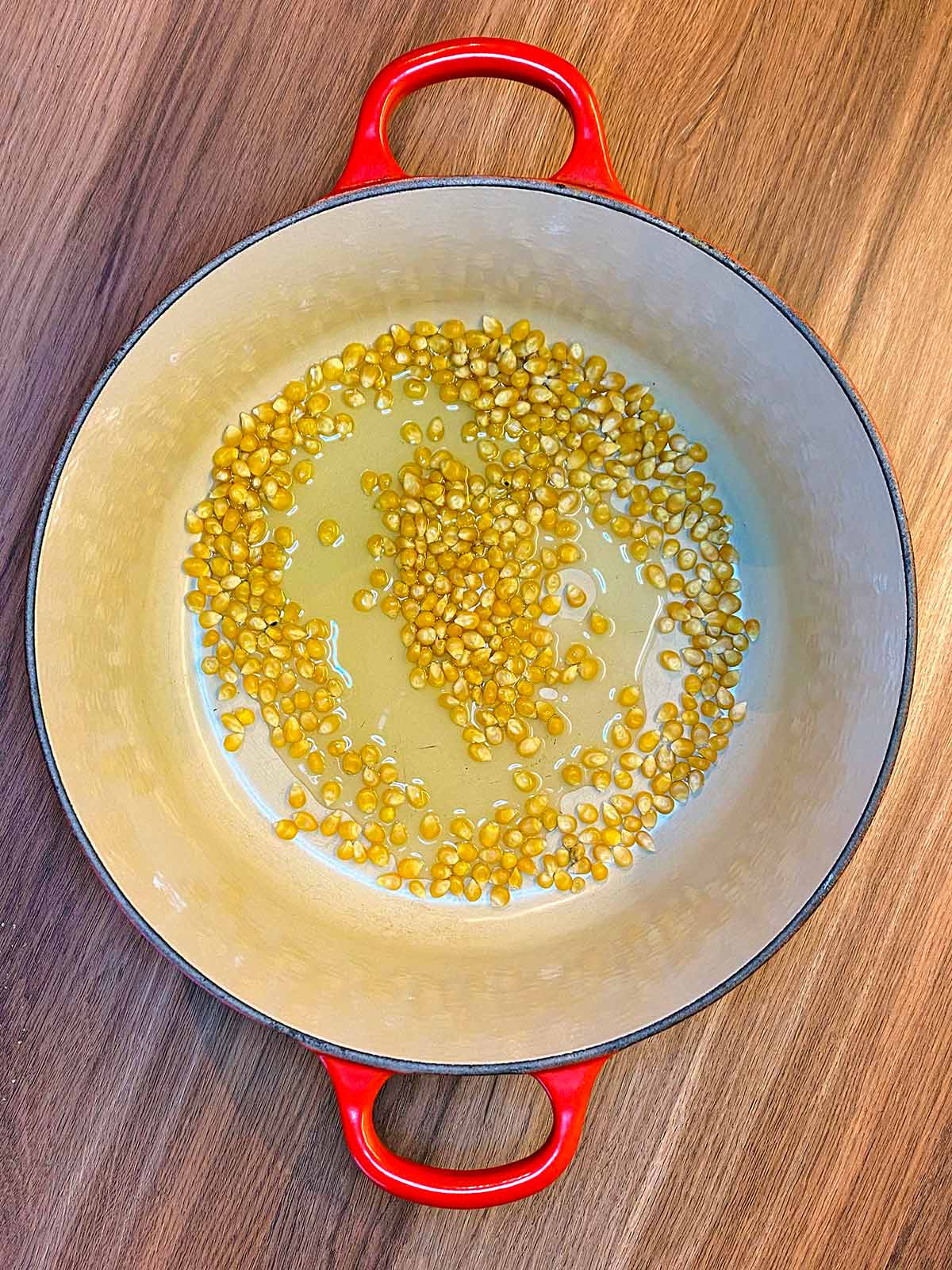 Corn kernels and oil in a large pan.