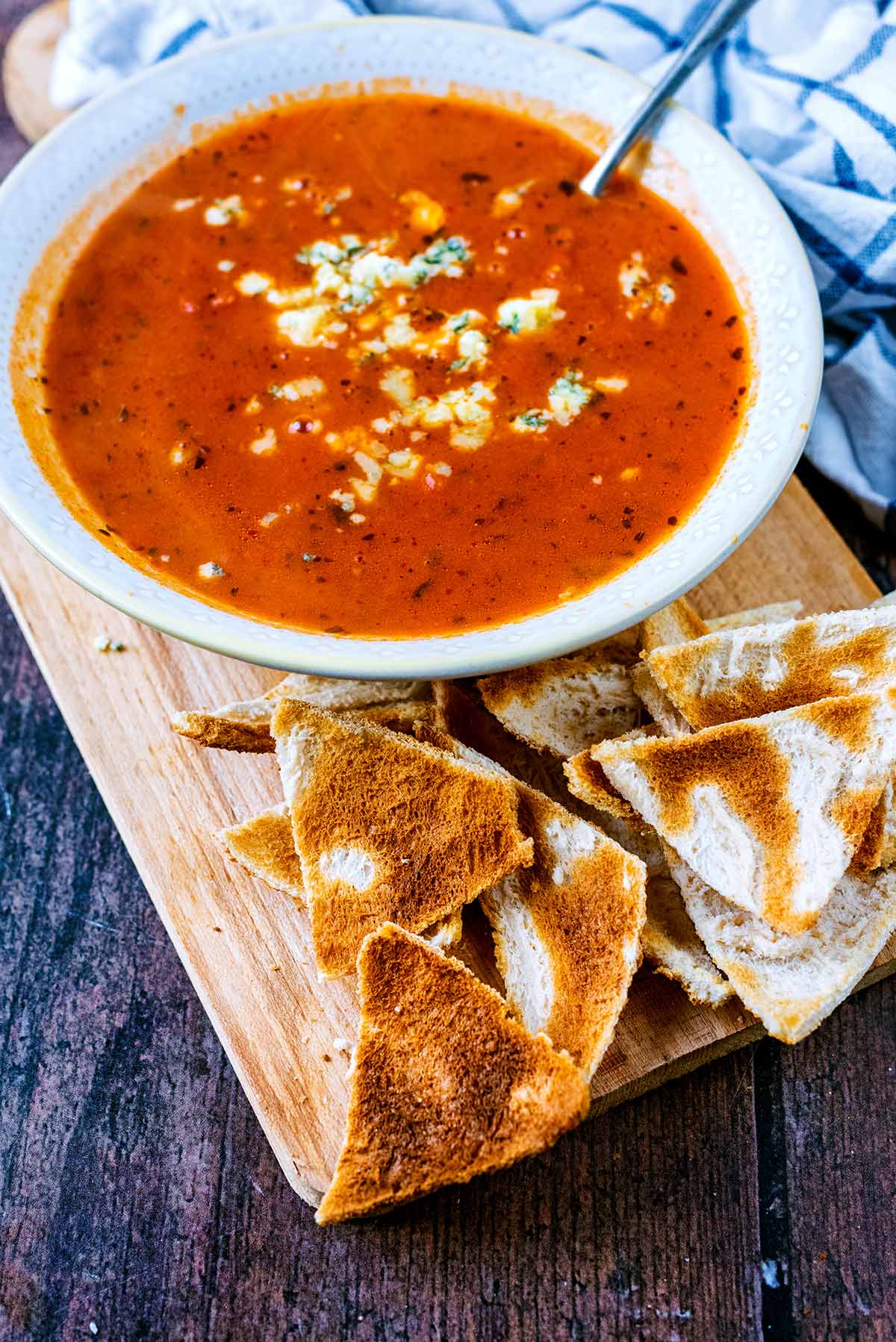 A bowl of tomato soup with some toast triangles in front of it.