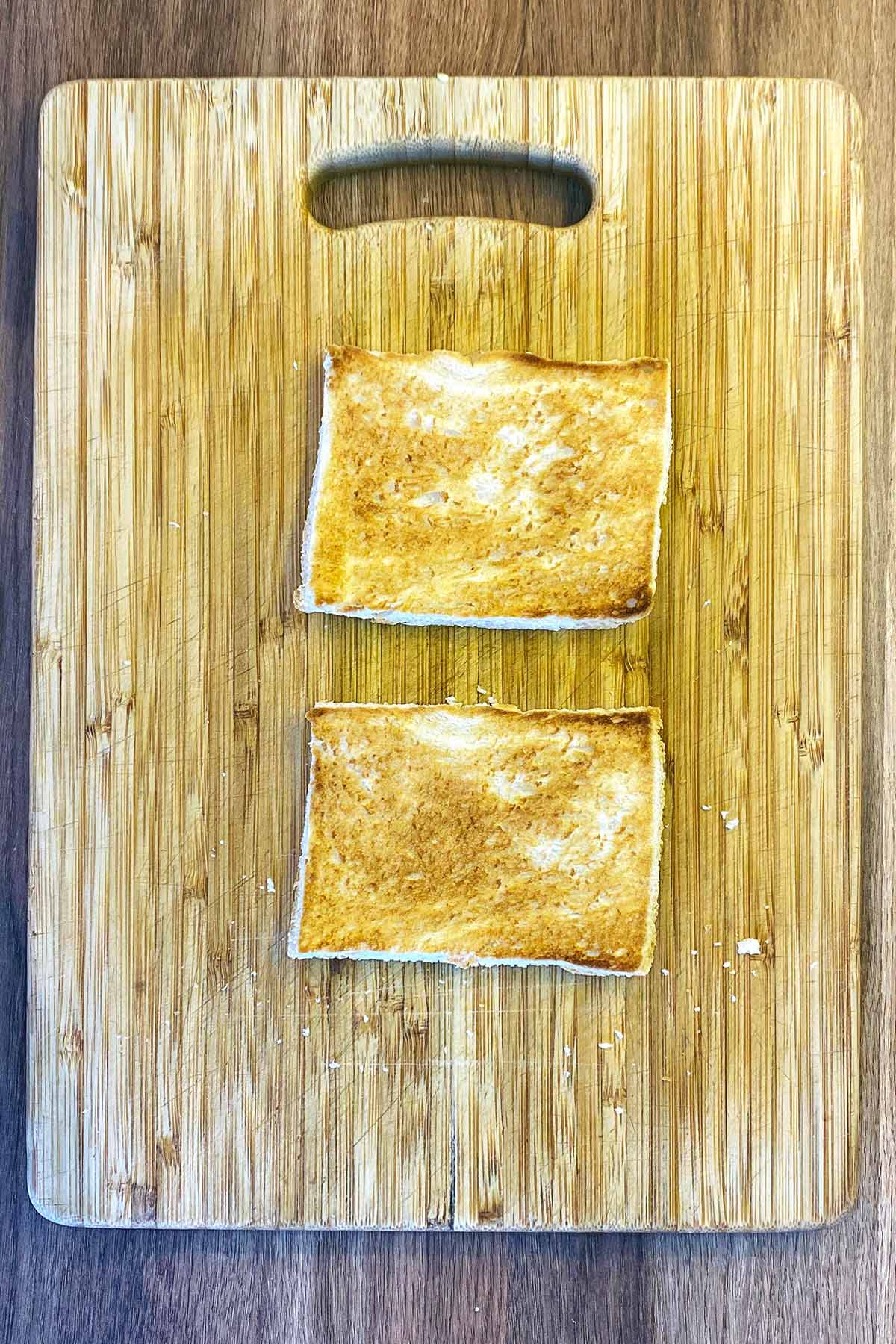Two slices of toast on a chopping board.