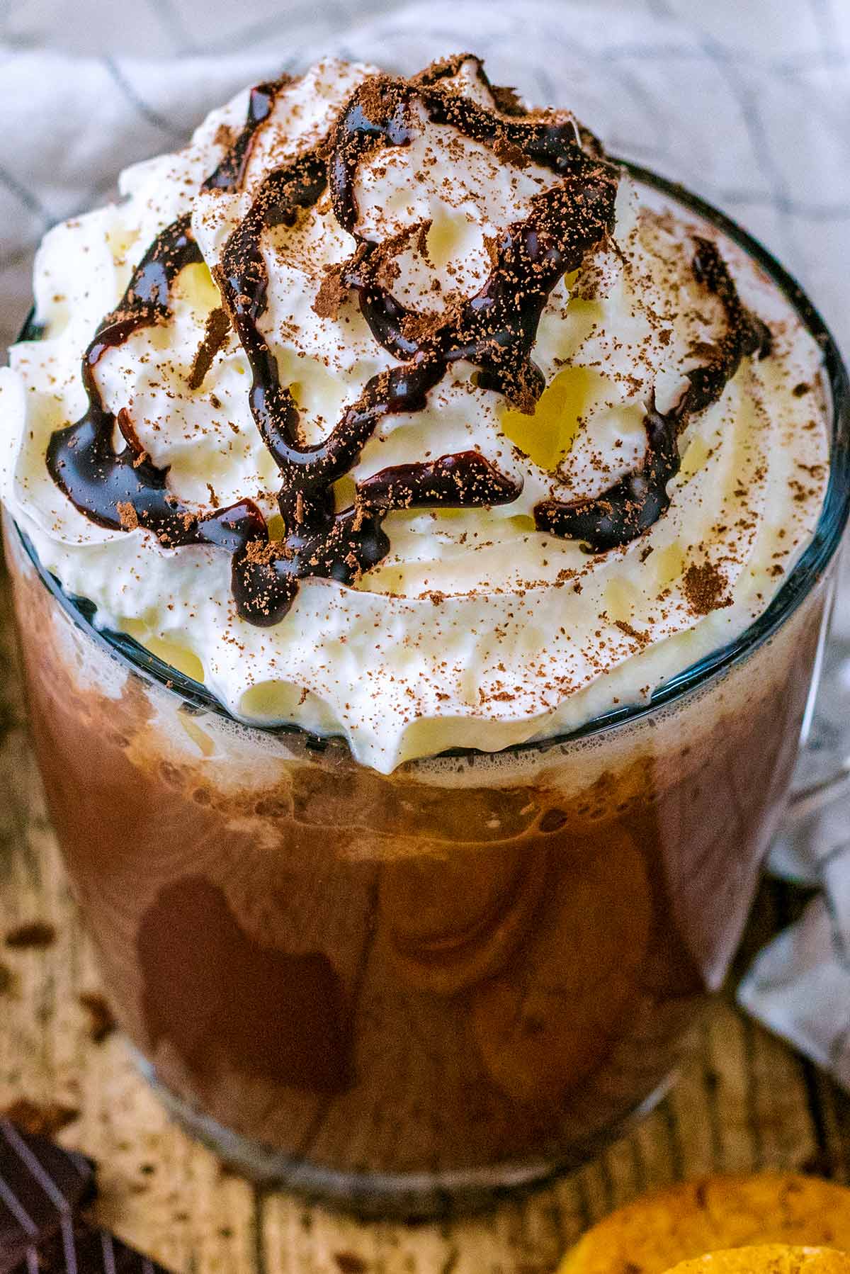 Whipped cream and chocolate sauce on top of a mug of hot chocolate.
