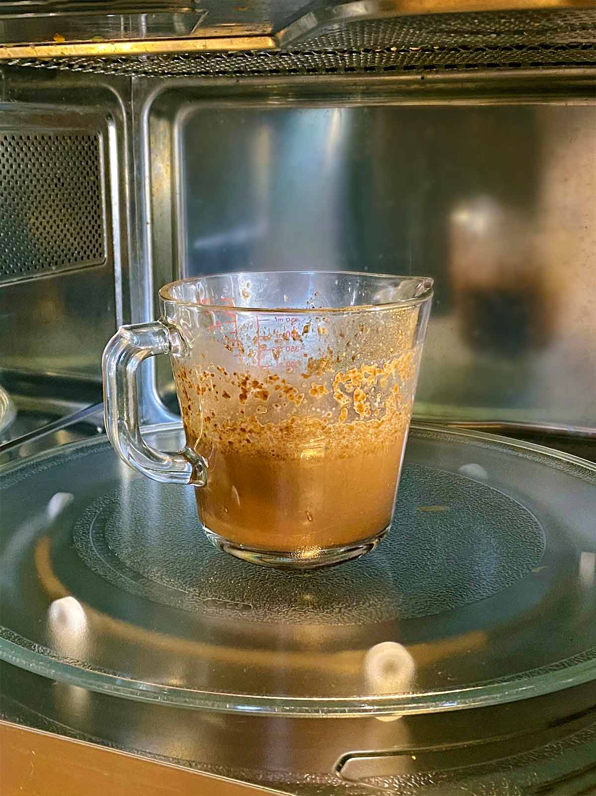 A jug of chocolate milk in a microwave.