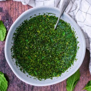 Homemade mint sauce in a small bowl with a spoon.