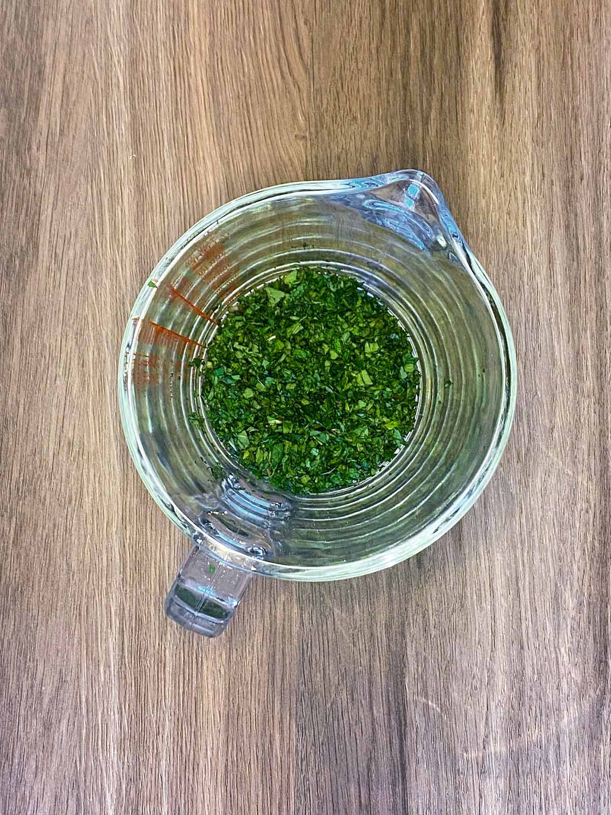 Chopped fresh mint in a glass jug.