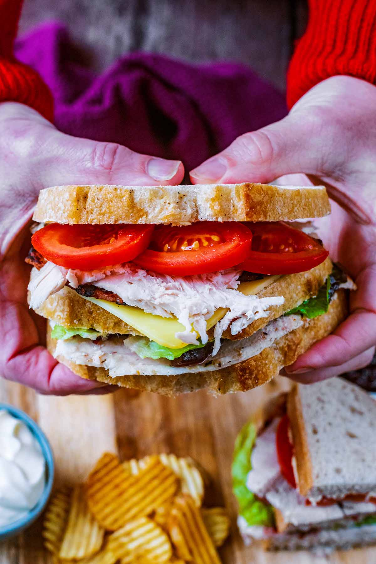 Two hands holding a double decker turkey sandwich.