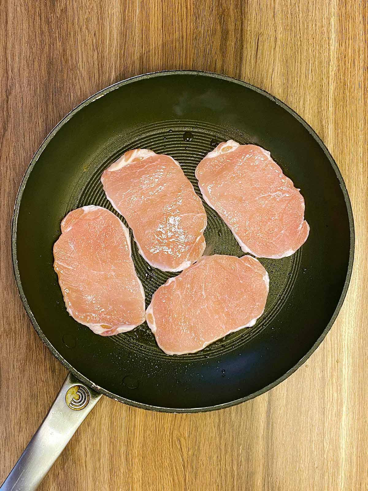 Bacon medallions cooking in a pan.
