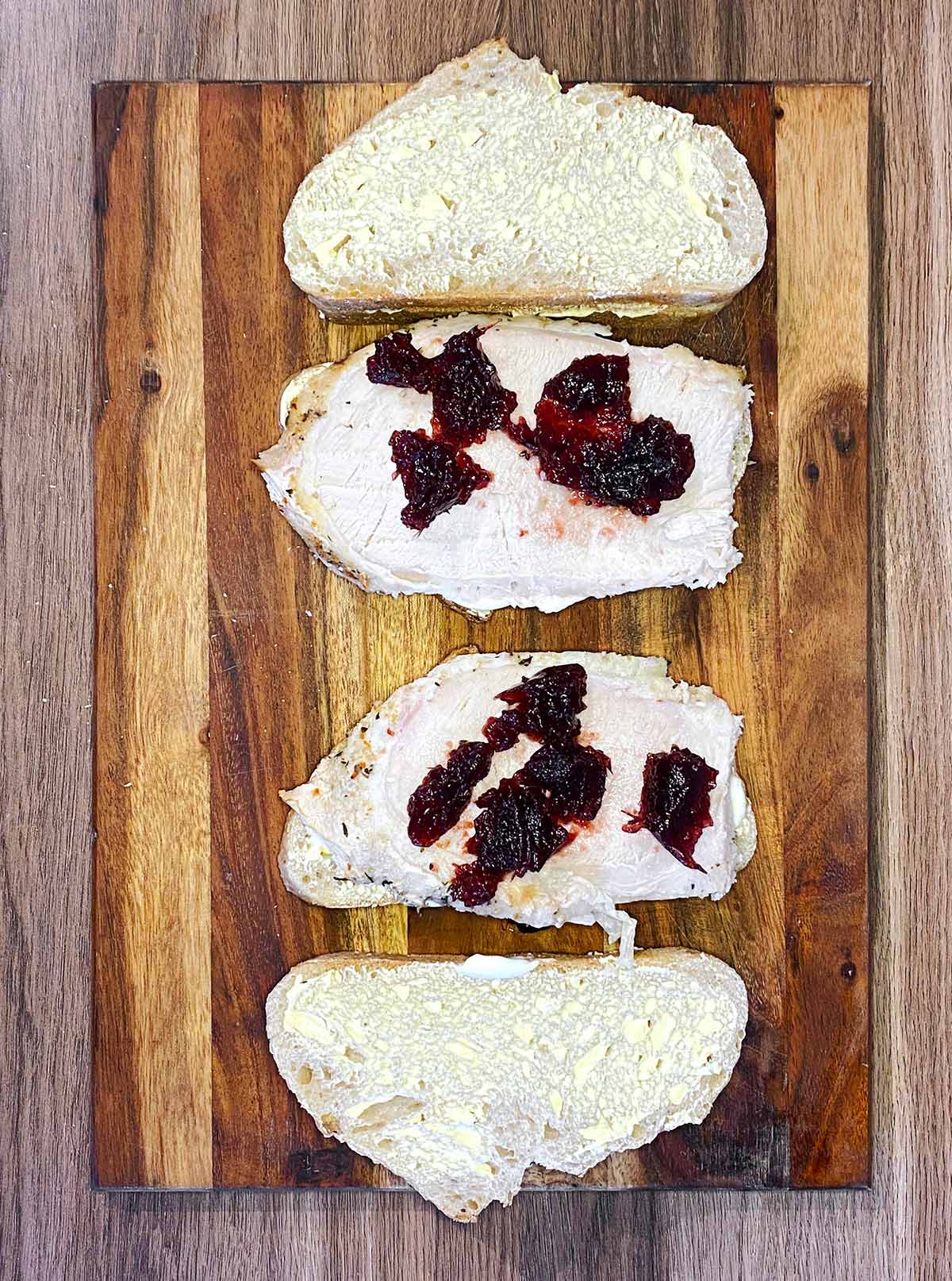 Slices of bread with turkey and cranberry sauce on it.