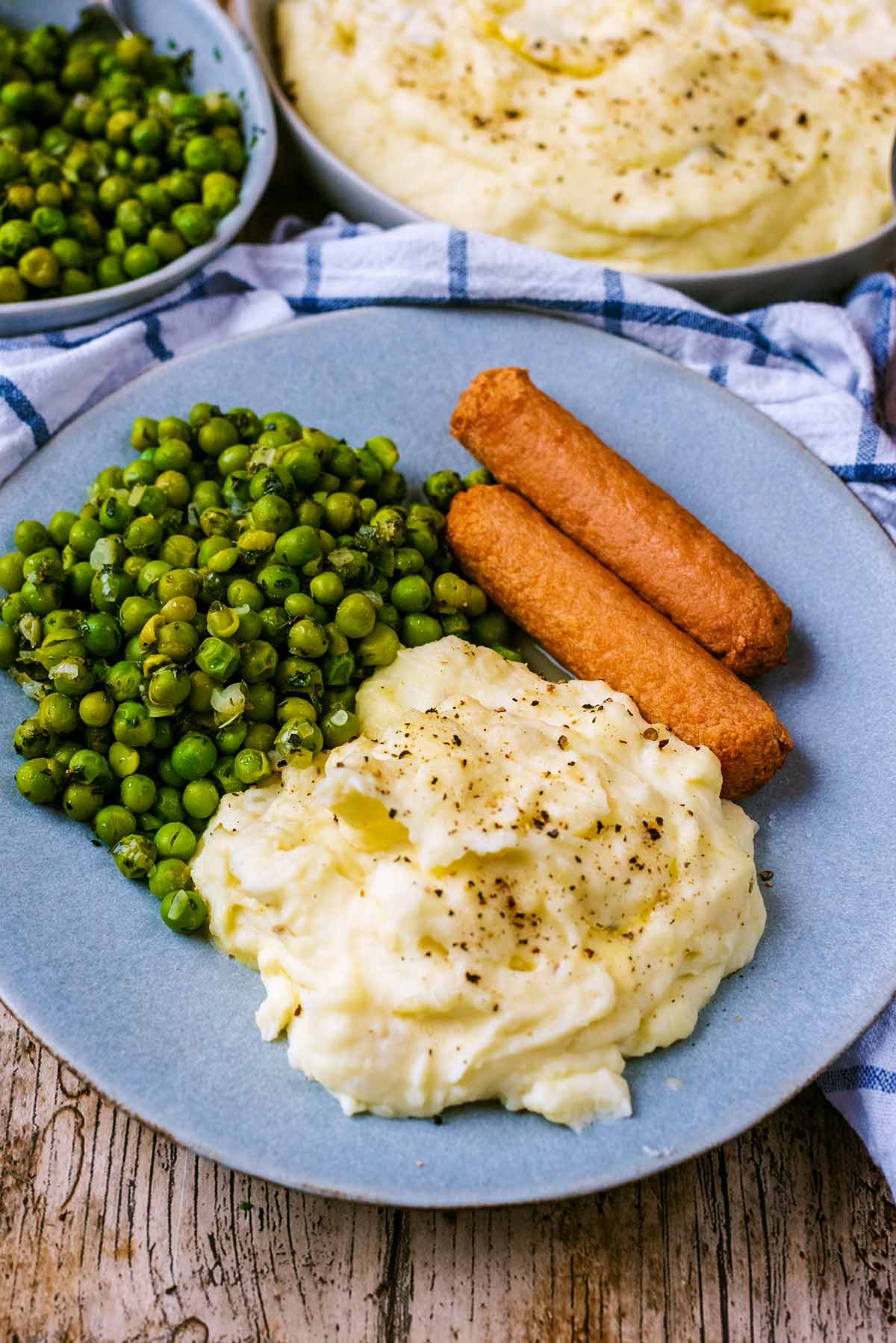 A plate of sausages, peas and mashed potatoes.