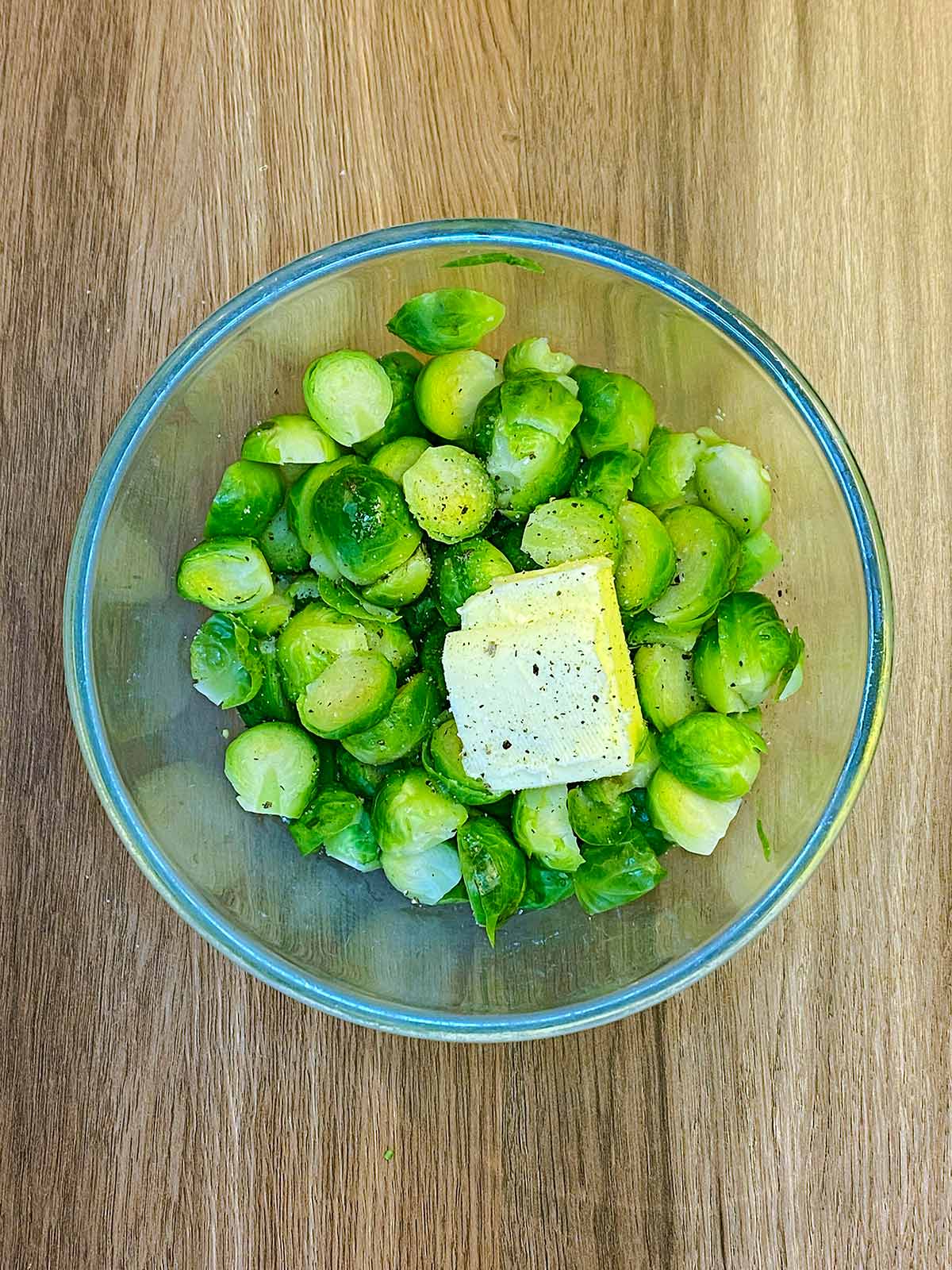 A bowl of cooked Brussles sprouts with butter and seasoning.