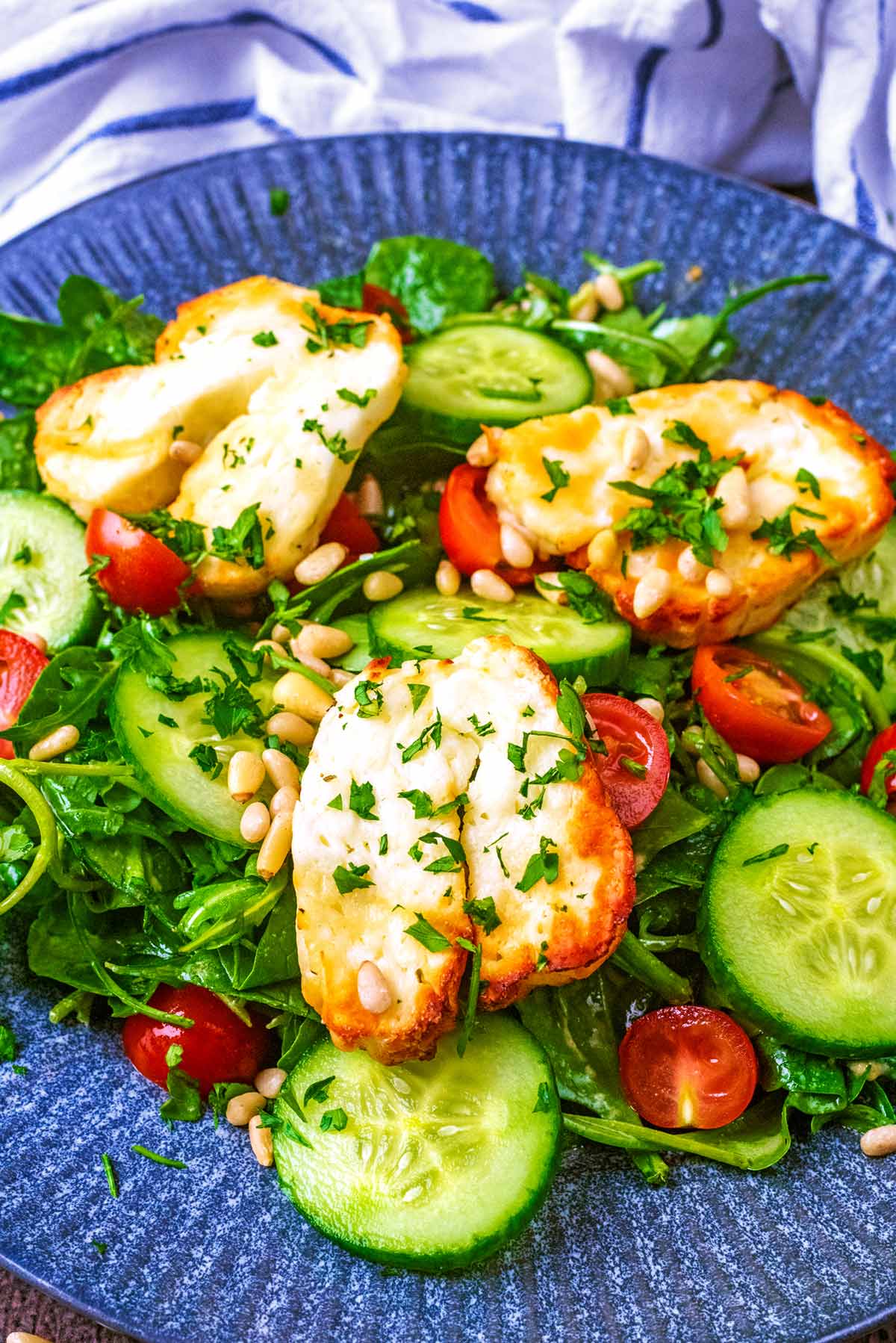 A salad topped with slices of cooked halloumi.