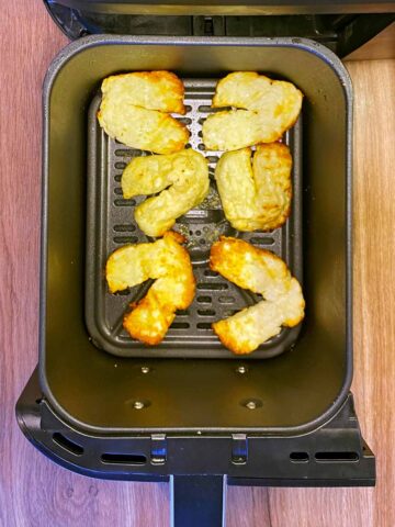 Cooked halloumi in an air fryer basket.