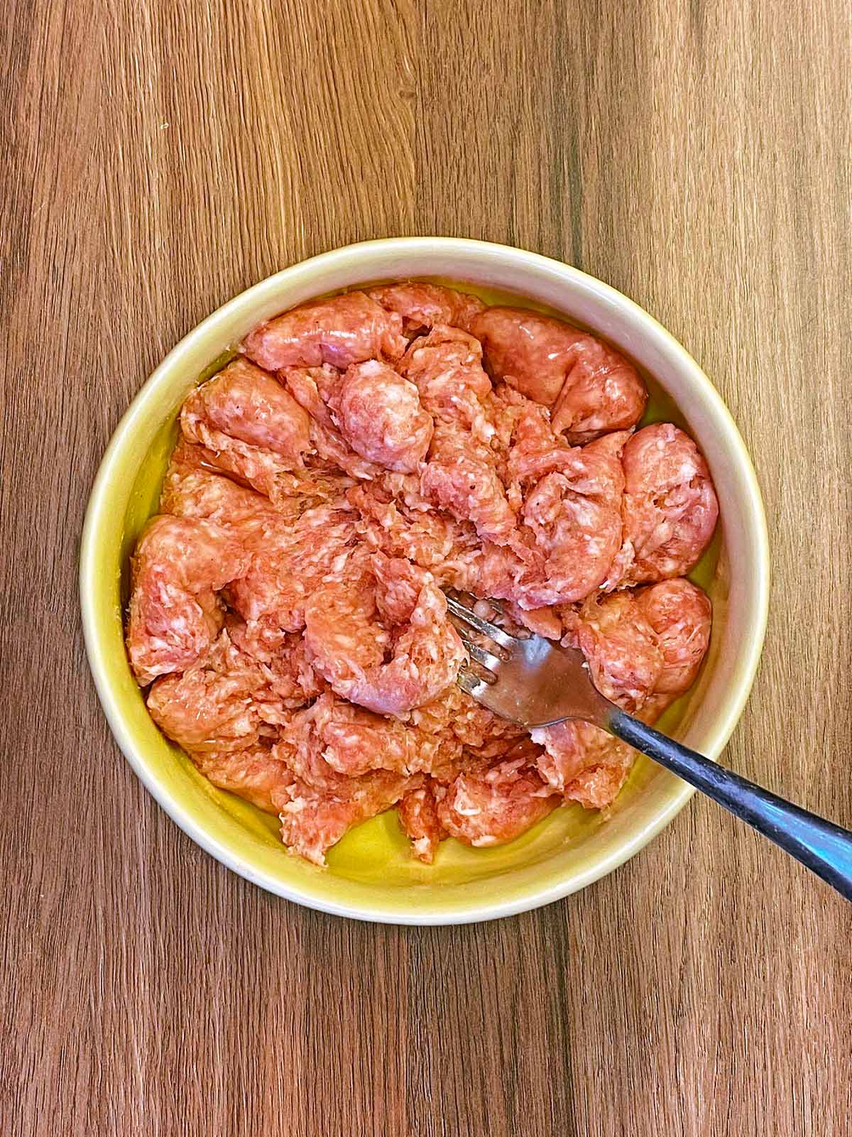 A bowl with mashed sausage meat in it.