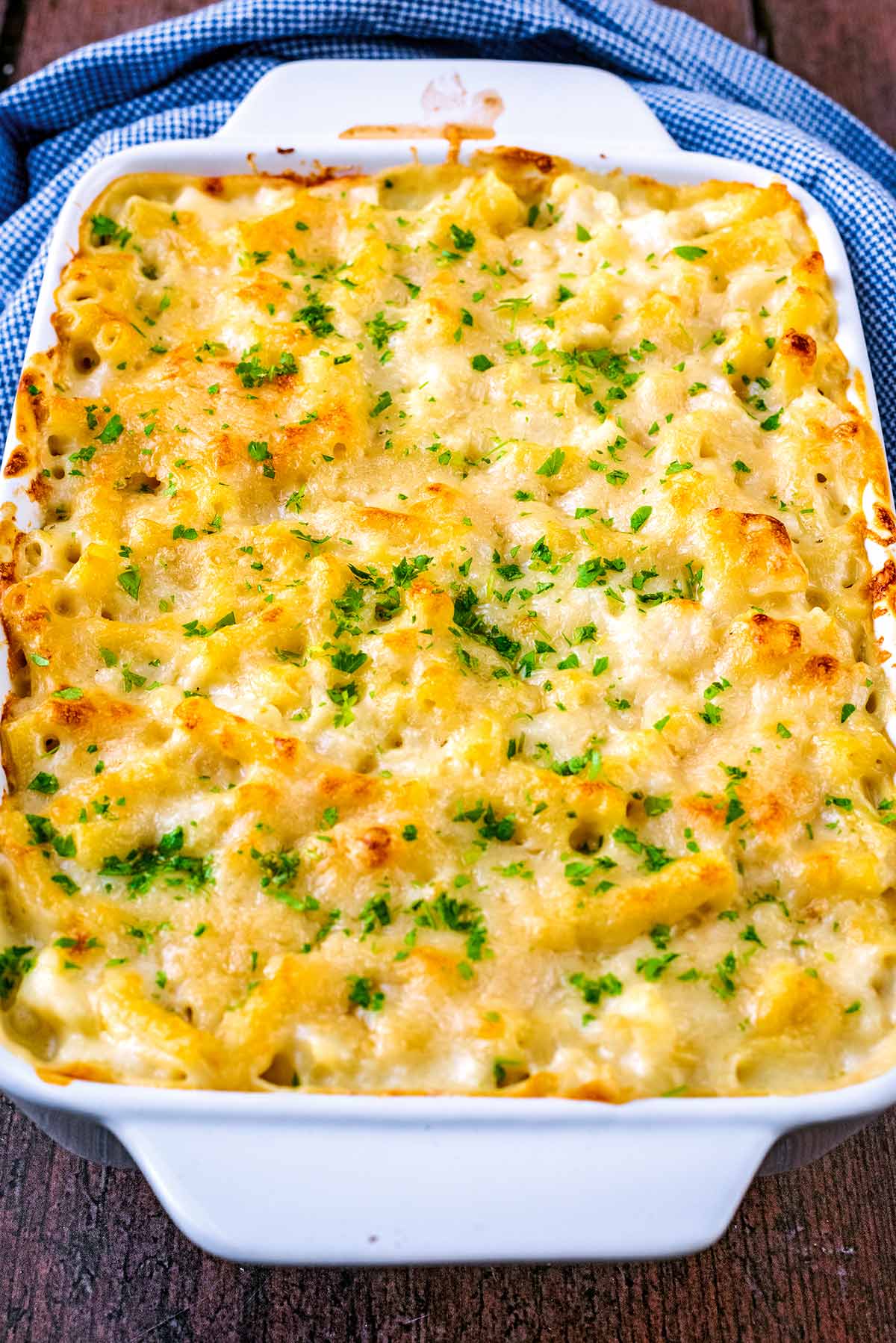 A dish of mac and cheese topped with finely chopped herbs.