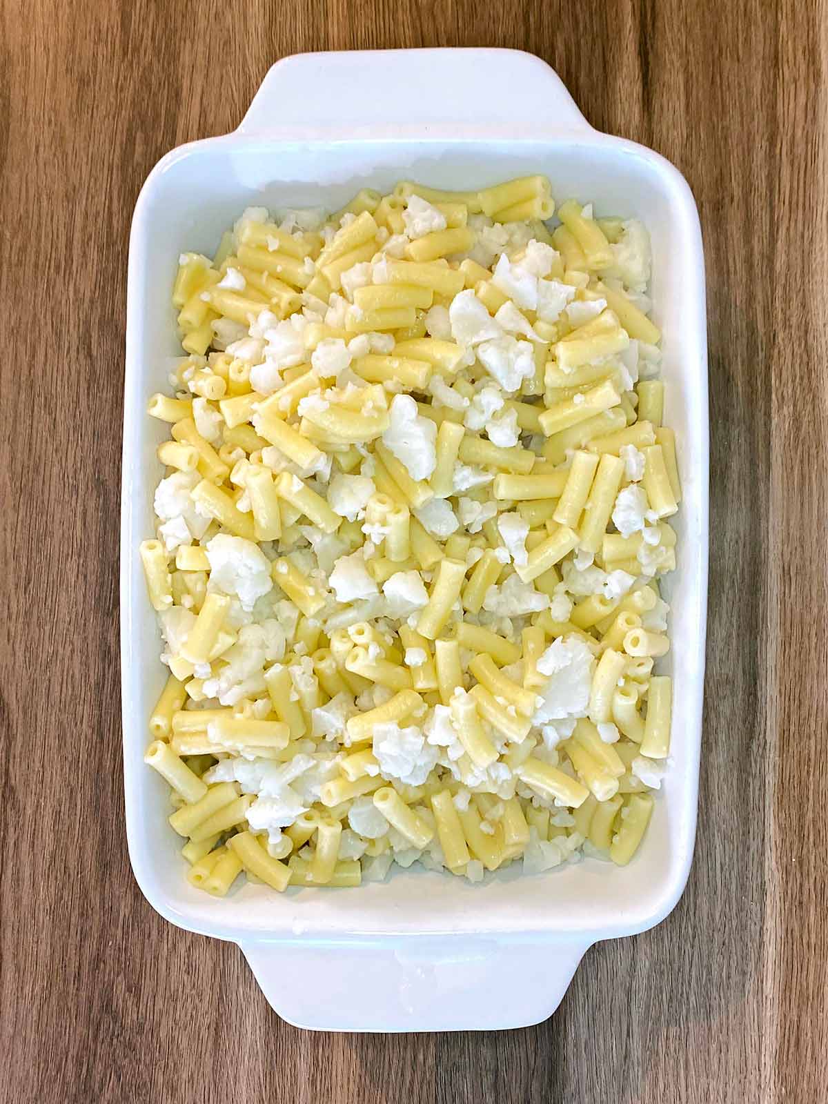 Drained pasta and cauliflower in a baking dish.
