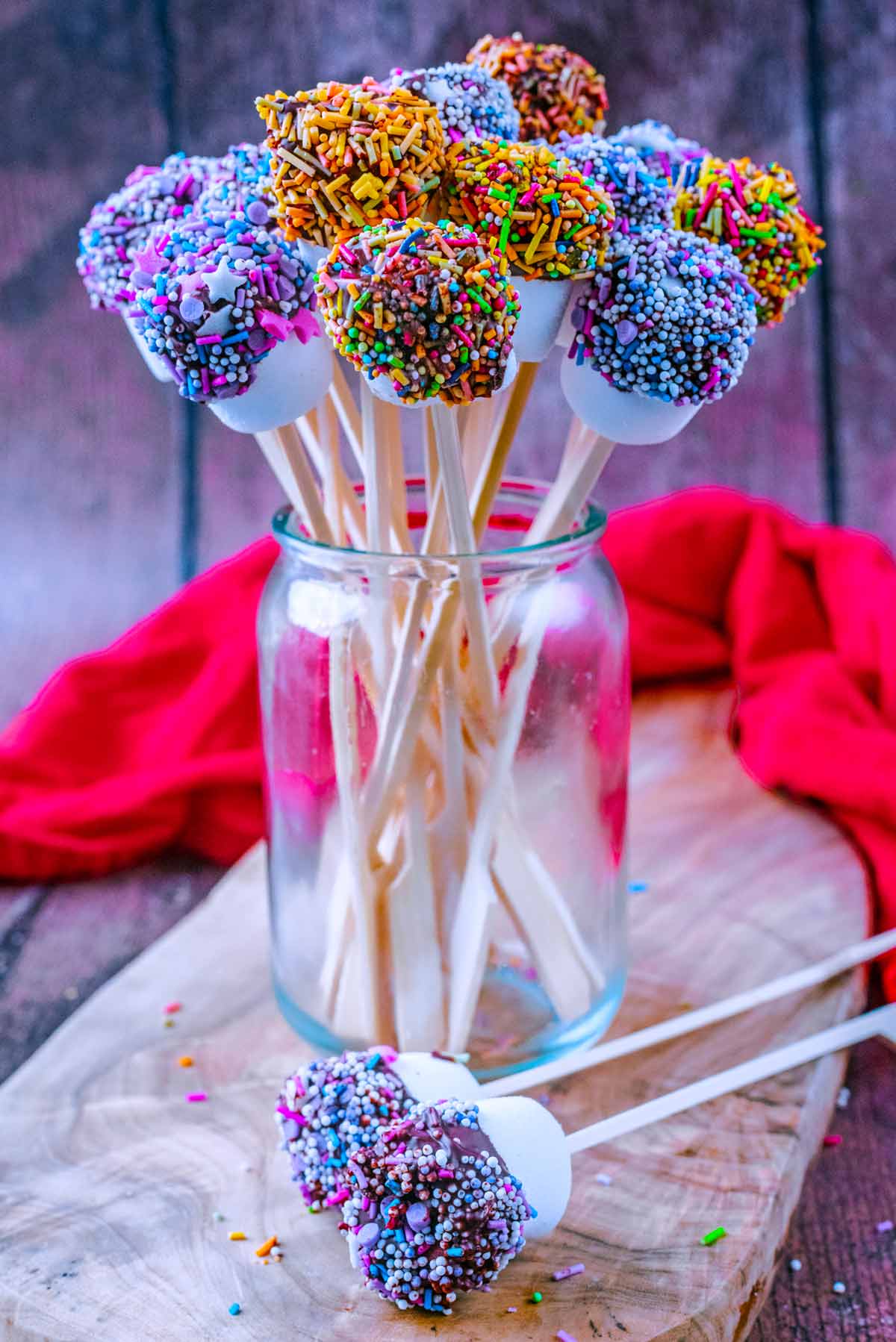 A glass jar with marshmallows on sticks in it, looking like a bunch of flowers.