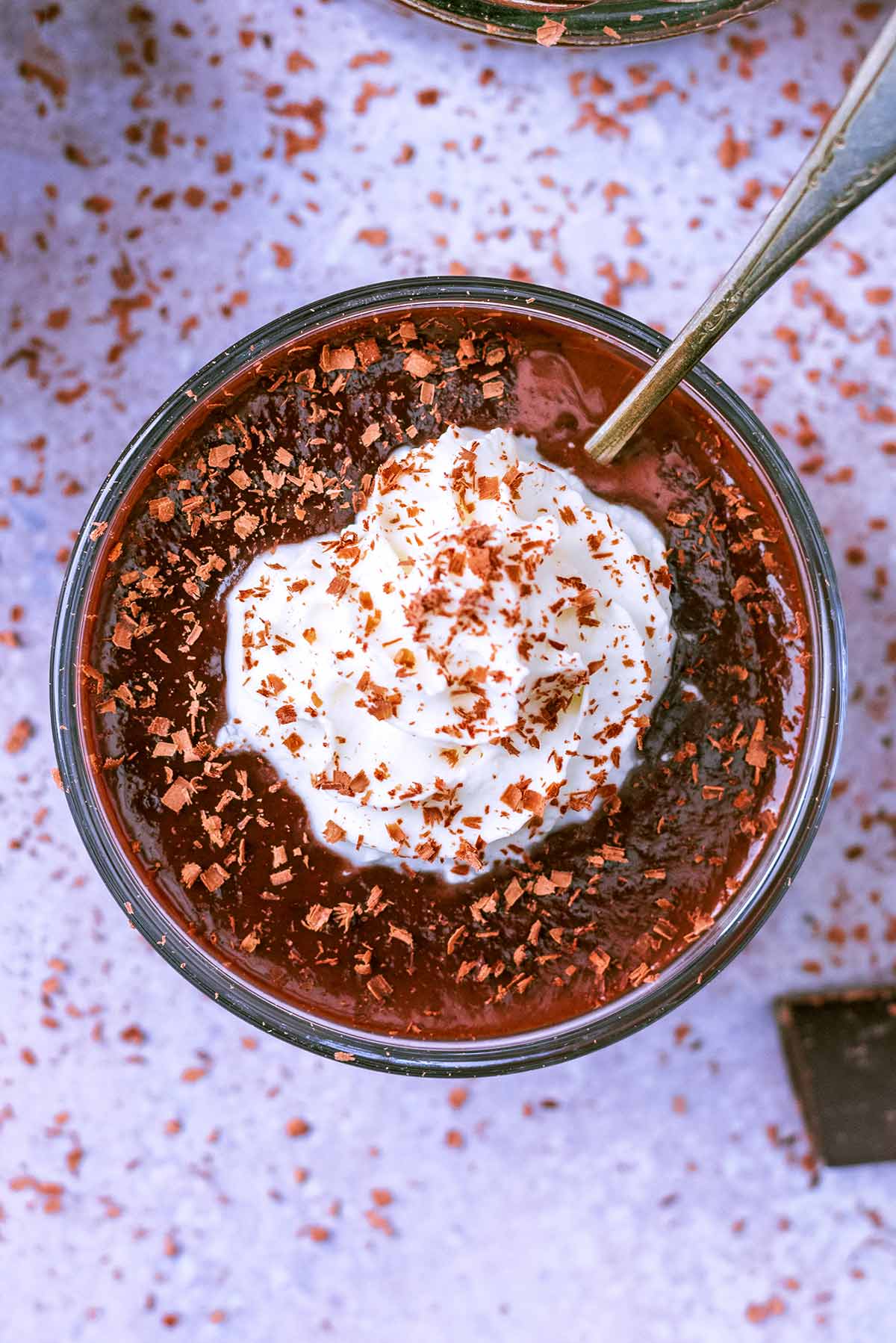 A pot of chocolate dessert with a dollop of whipped cream on top.