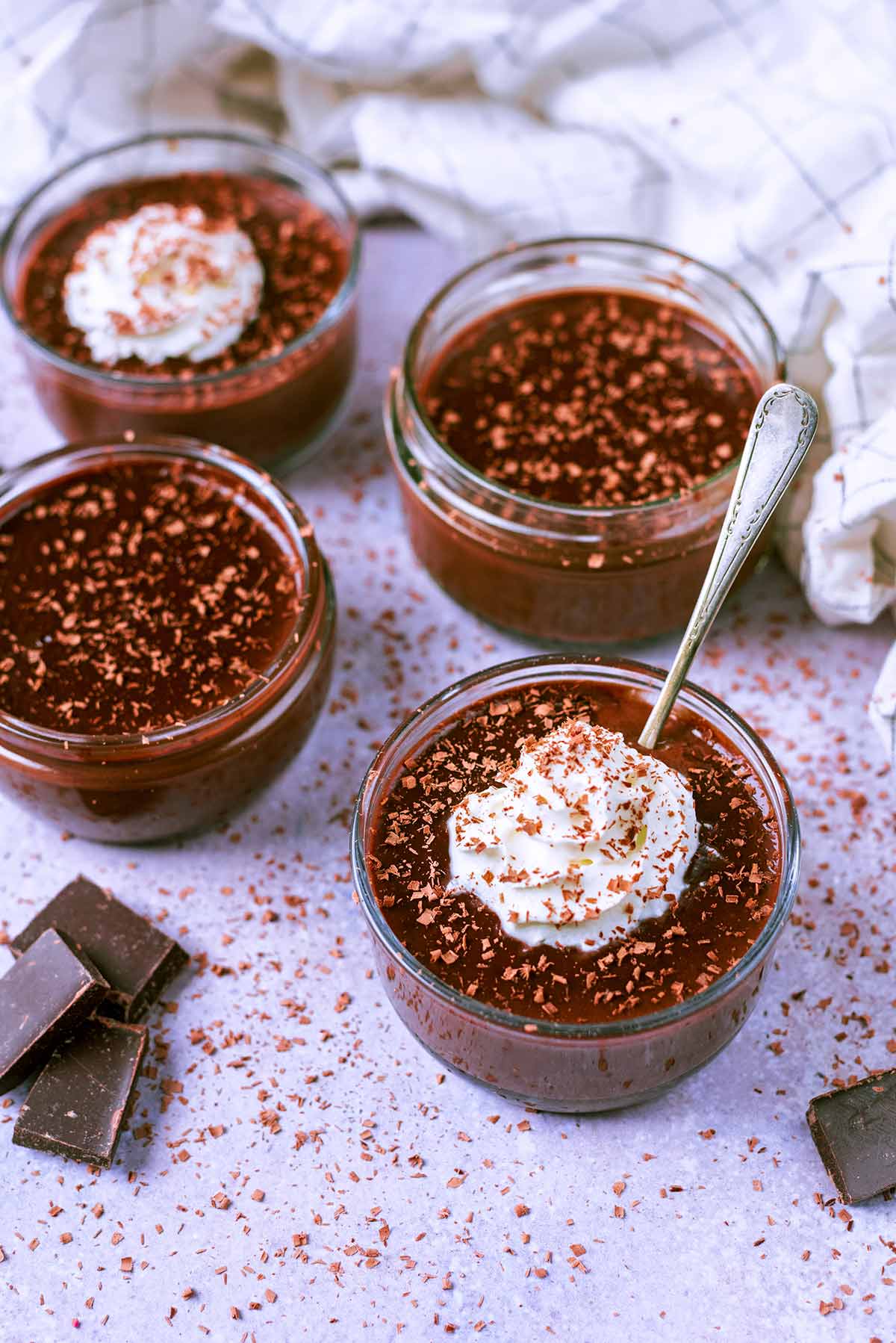 Four chocolate pots surrounded by chocolate shavings.
