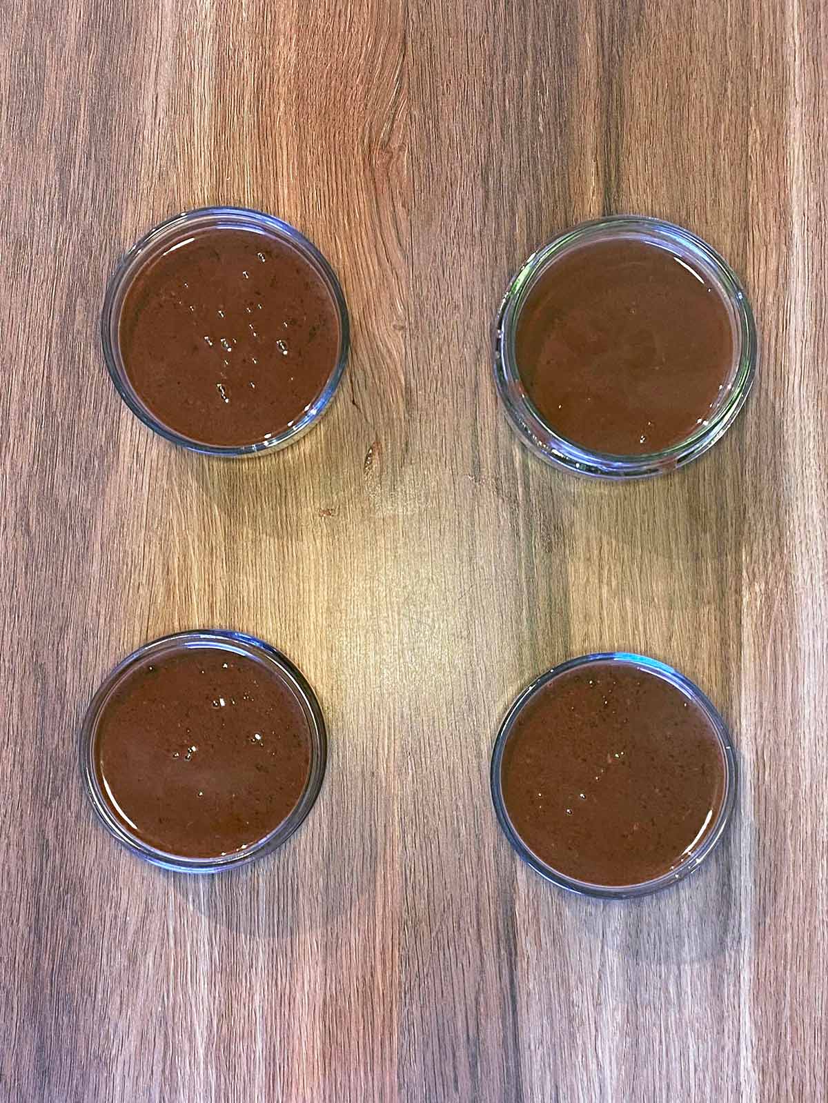 Four glass ramekins filled with the chocolate mixture.