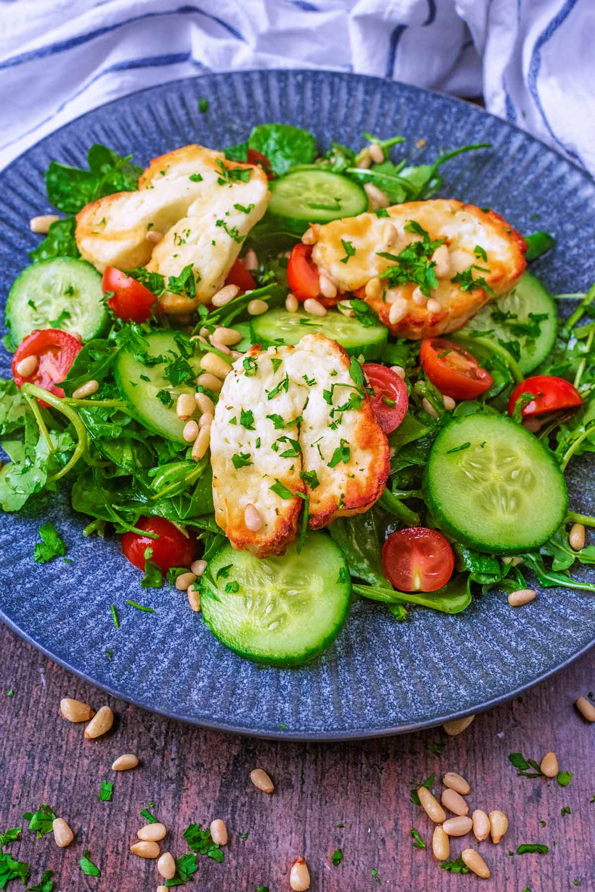 A plate of halloumi salad with pine nuts scattered around it.