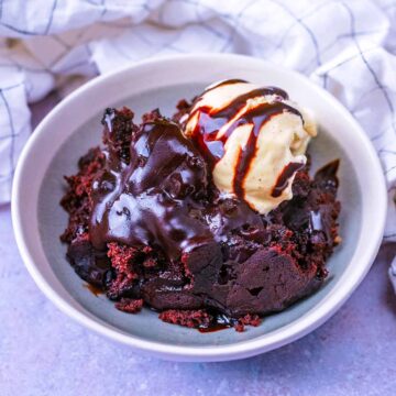 Slow cooker chocolate cake in a bowl with a ball of vanilla ice cream.