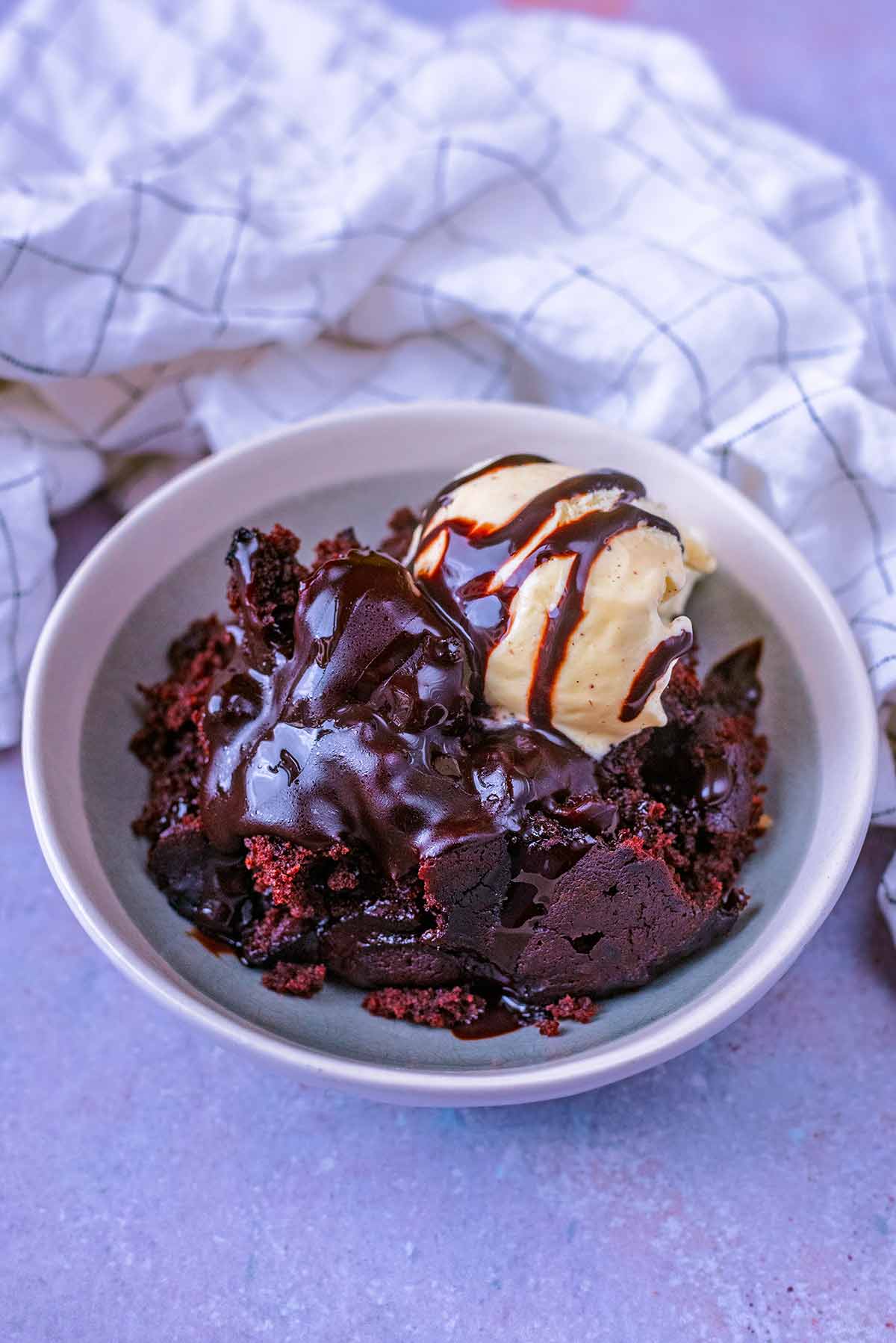 A bowl of chocolate cake and ice cream, covered in chocolate sauce.
