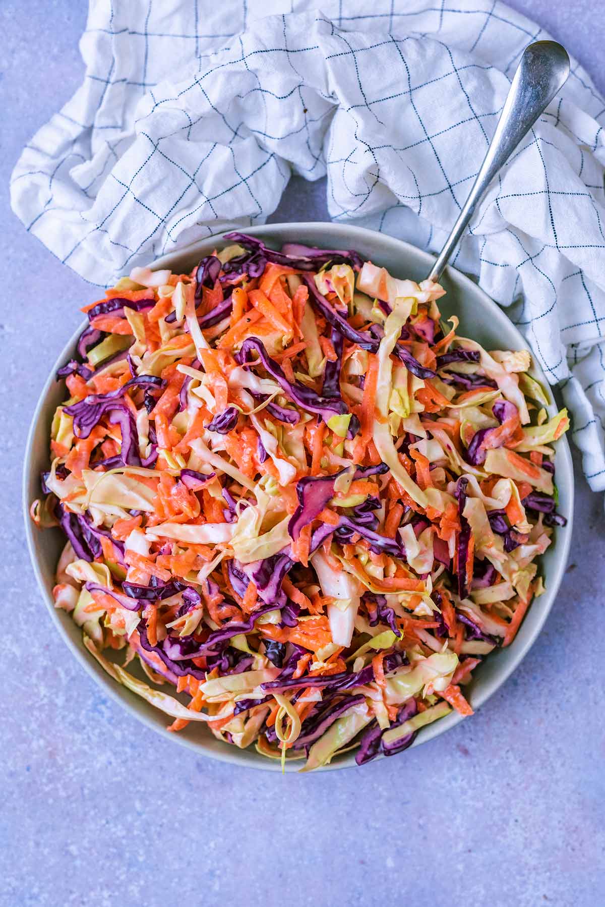 A large plate of coleslaw with a fork sticking out of it.