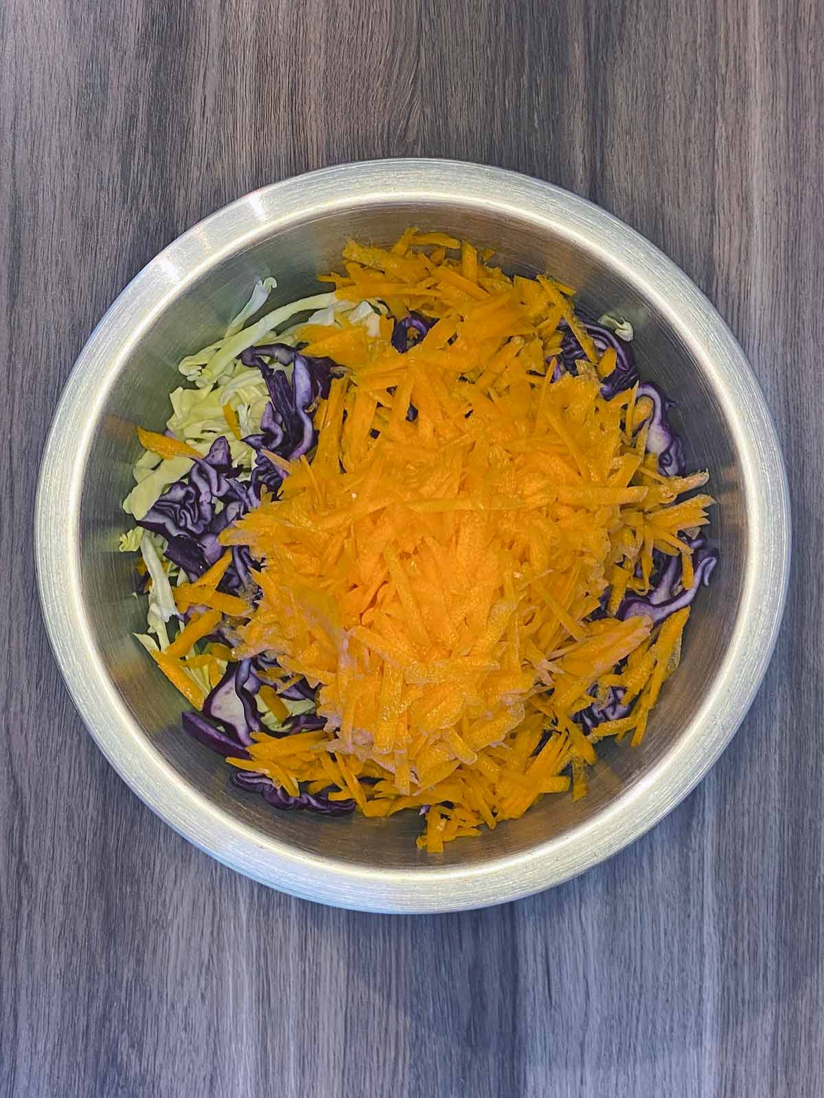 A bowl containing shredded cabbage and carrot.