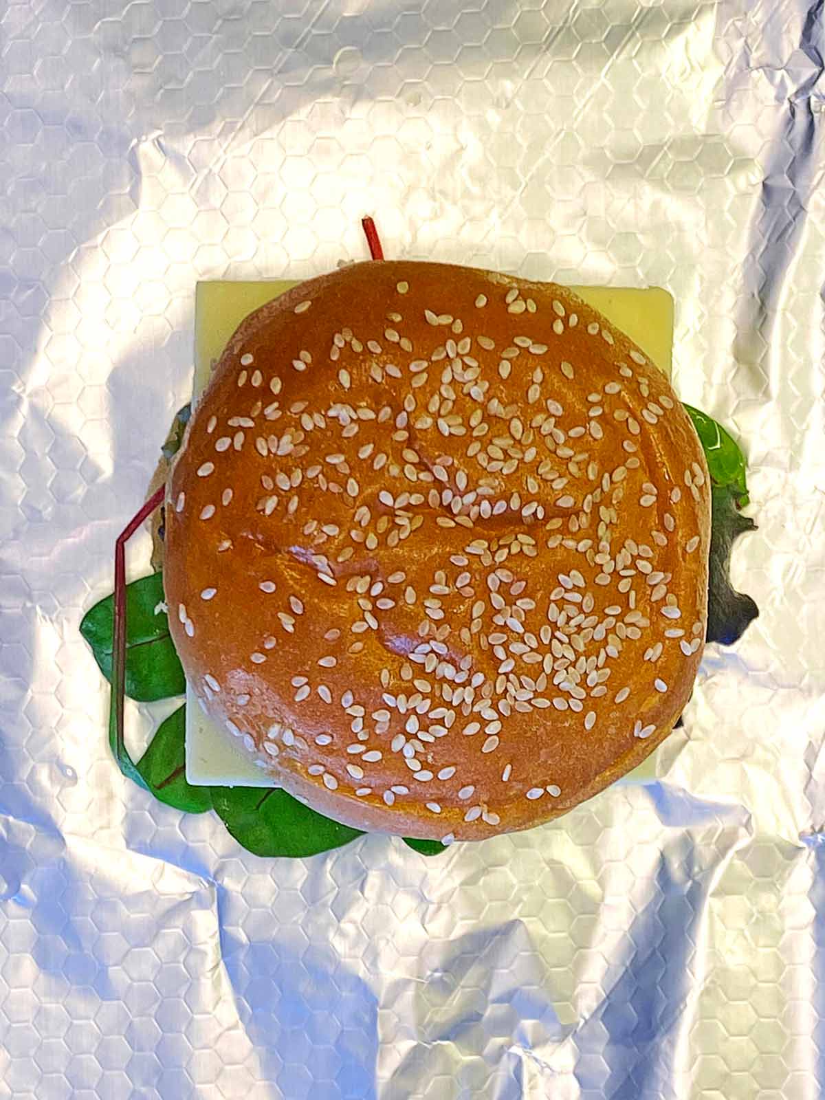 A hamburger sat on some foil.