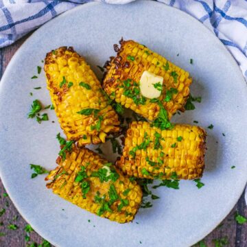 Air fryer Corn on the Cob on a round grey plate.