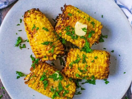 Air fryer Corn on the Cob on a round grey plate.