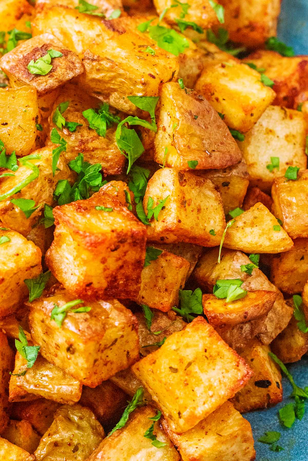 Cubes of cooked potato topped with chopped herbs.