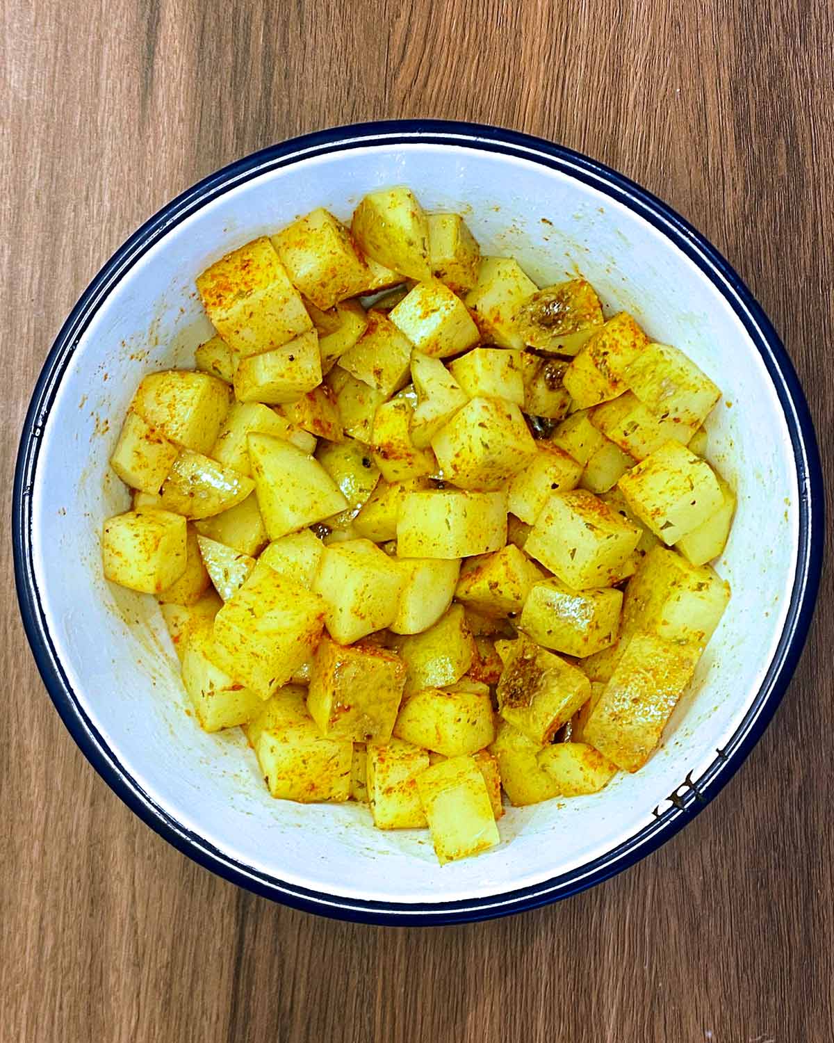 The potato cubes, oil and spices all mixed together.