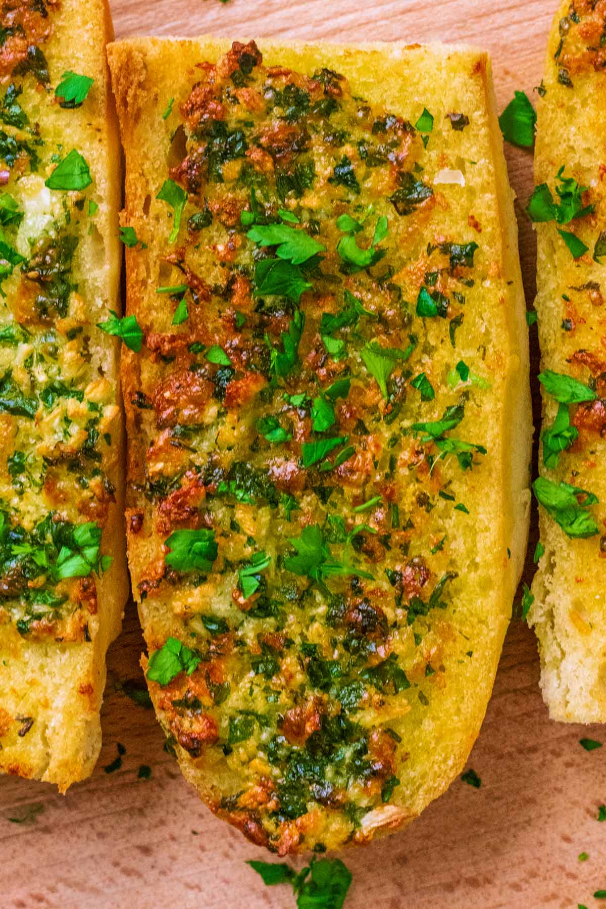 A slice of garlic bread topped with chopped parsley.