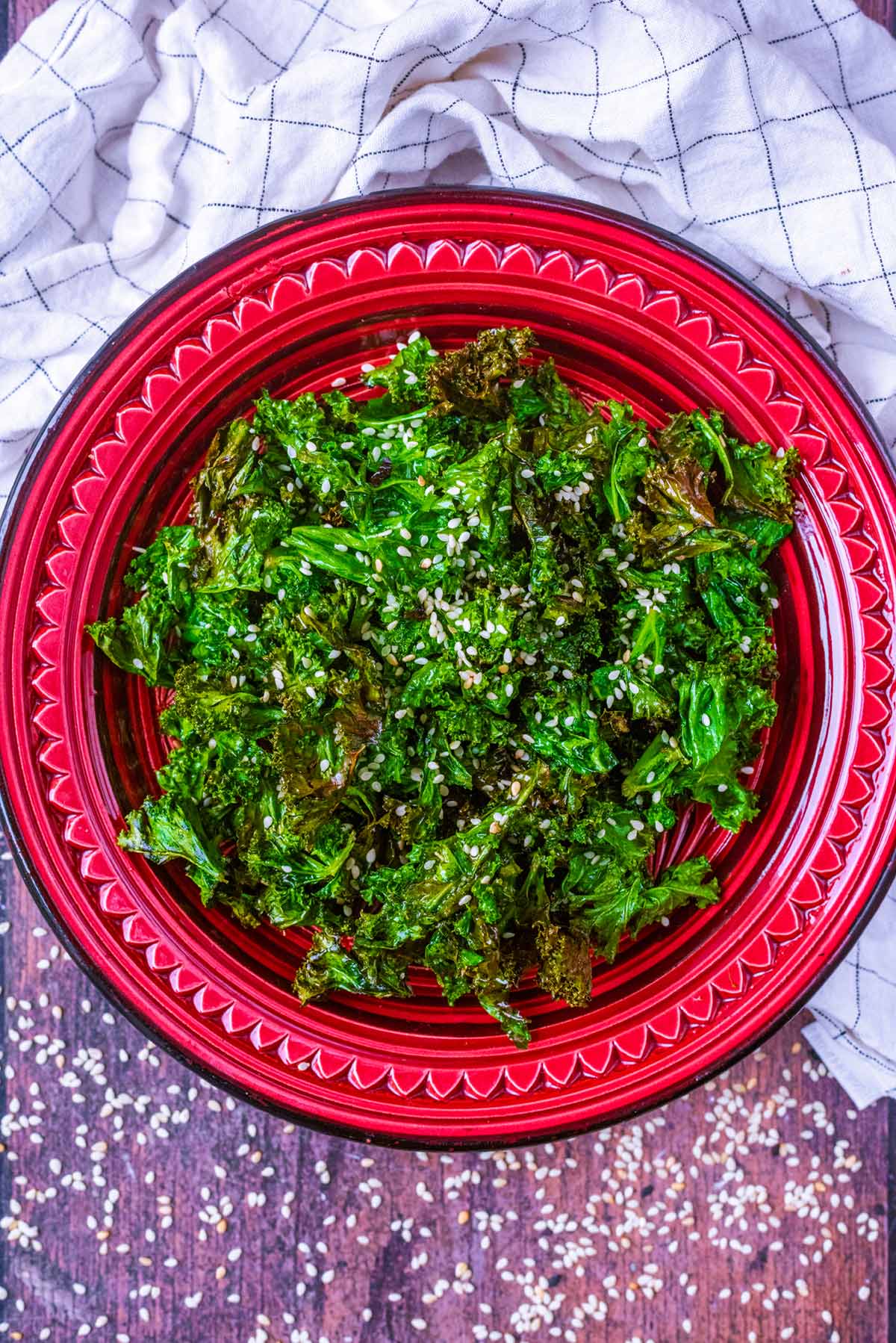 A bowl of cooked kale surrounded by sesame seeds.