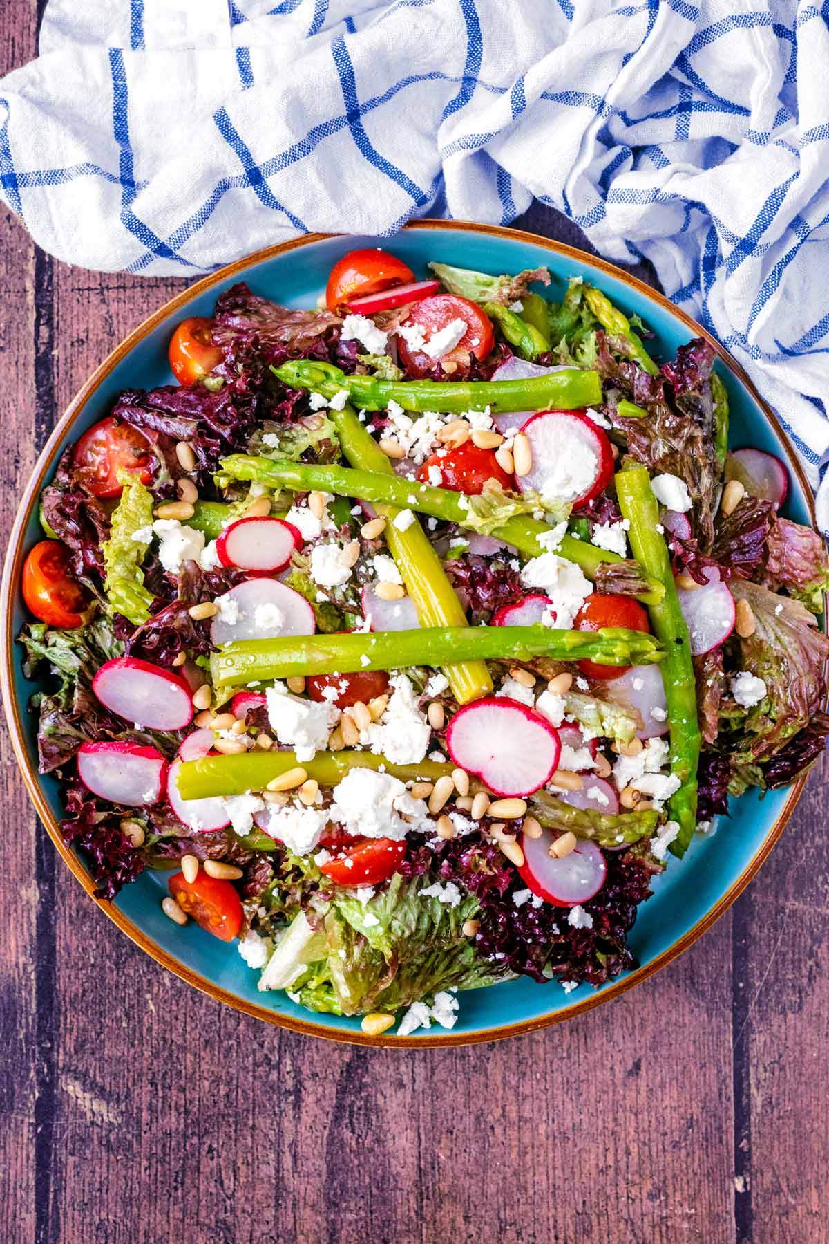 A plate of salad topped with asparagus spears and crumbled feta cheese.