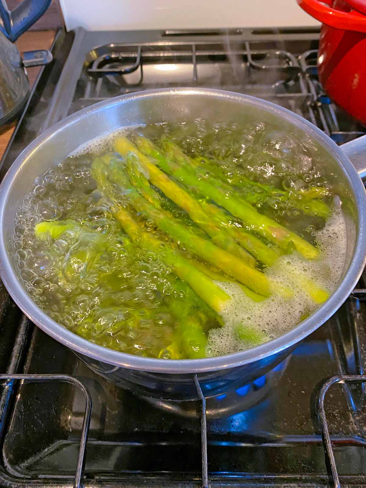 Asparagus in a pan of simmering water.