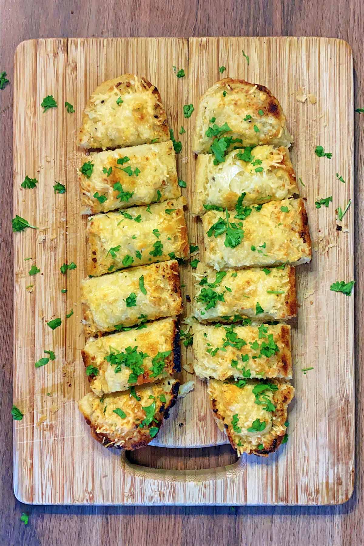 The garlic bread cut into slices with chopped parsley sprinkled over.