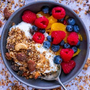 Low sugar granola in a bowl with yogurt and berries.