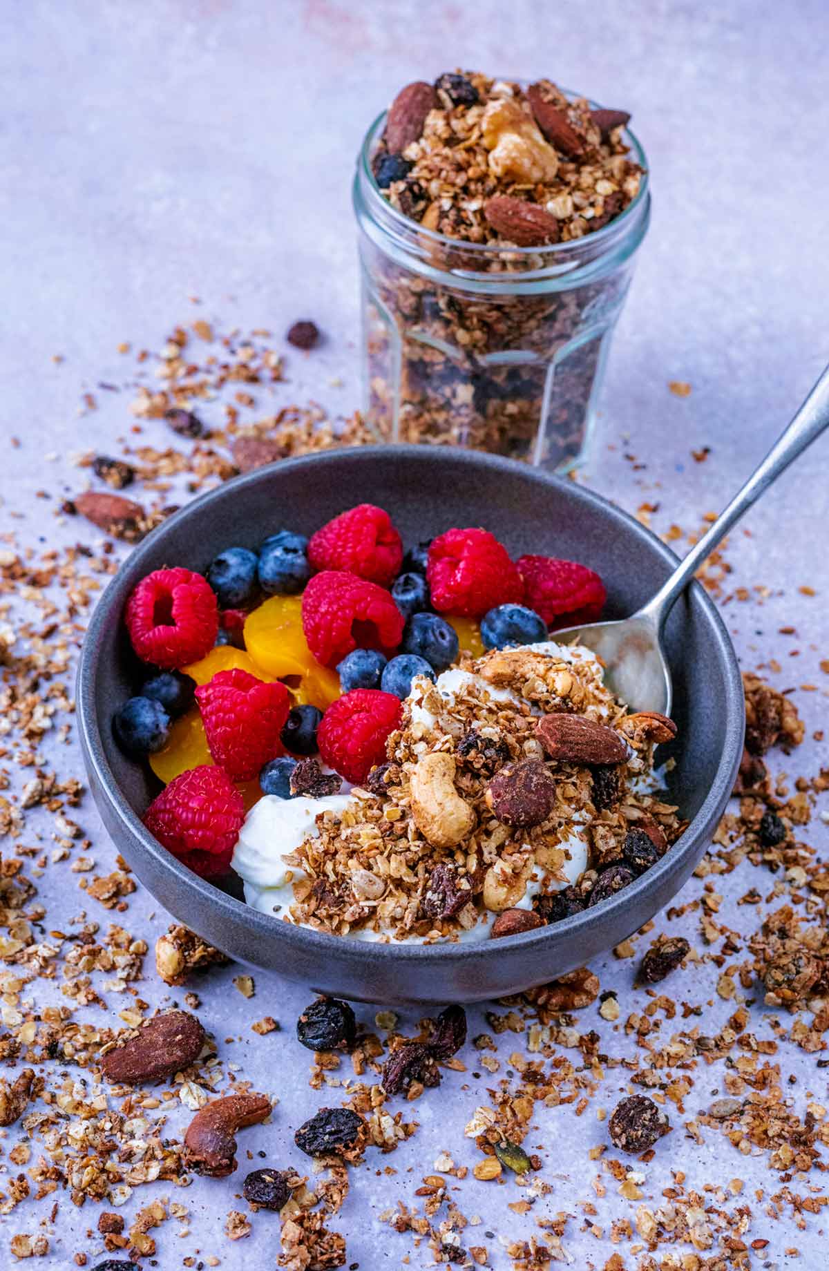 A bowl of yogurt and granola in front of a jar of more granola.