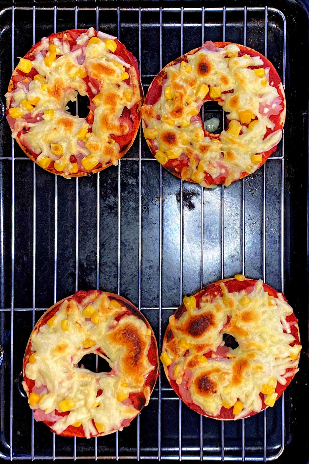 A grill pan with cooked pizza bagels on it.