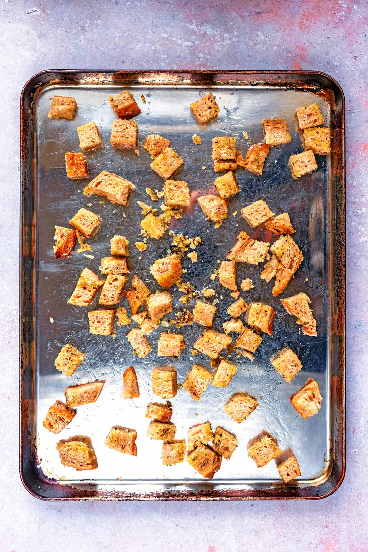 The bread cubes spread out over a baking tray.