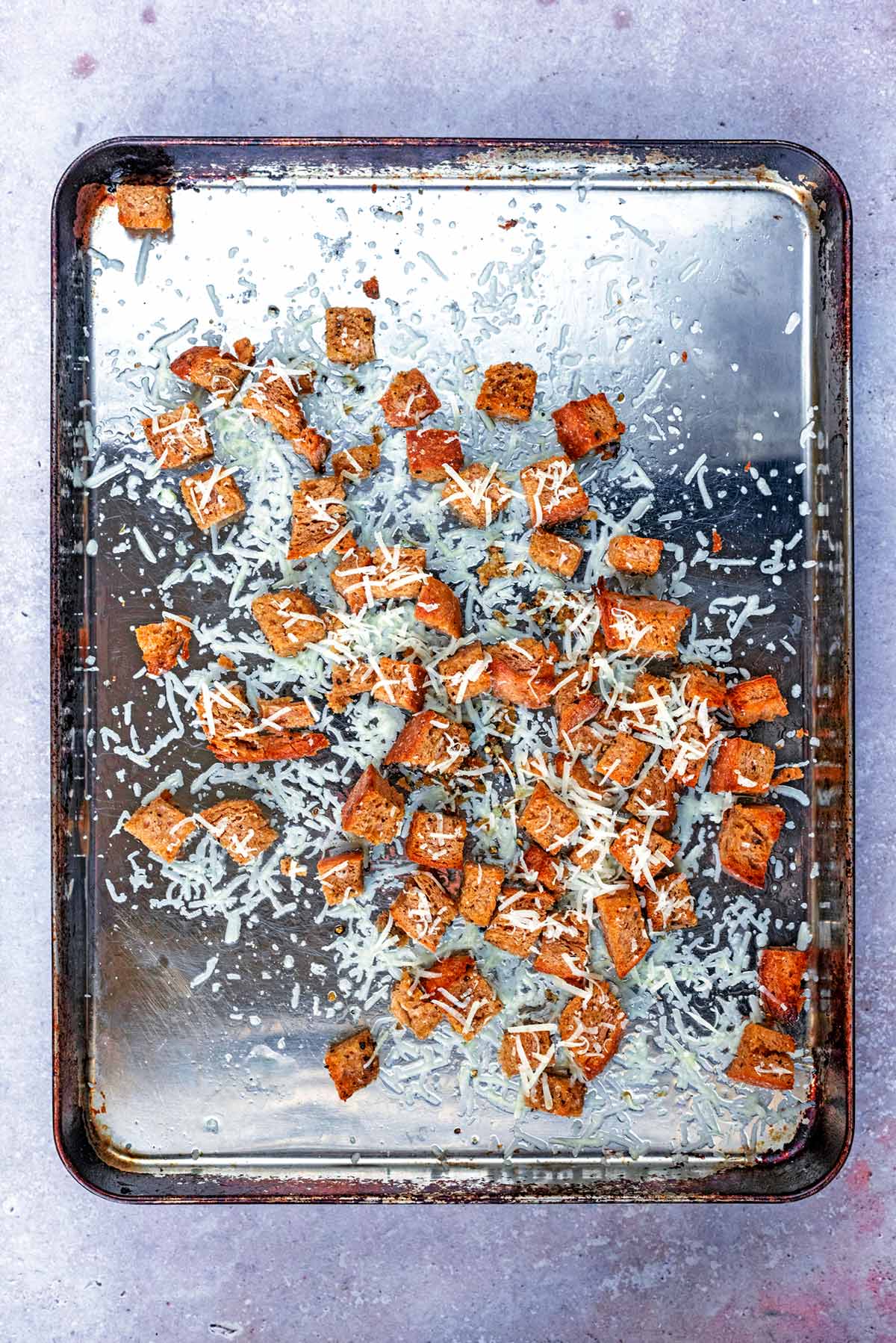 Croutons and grated Parmesan on a baking tray.