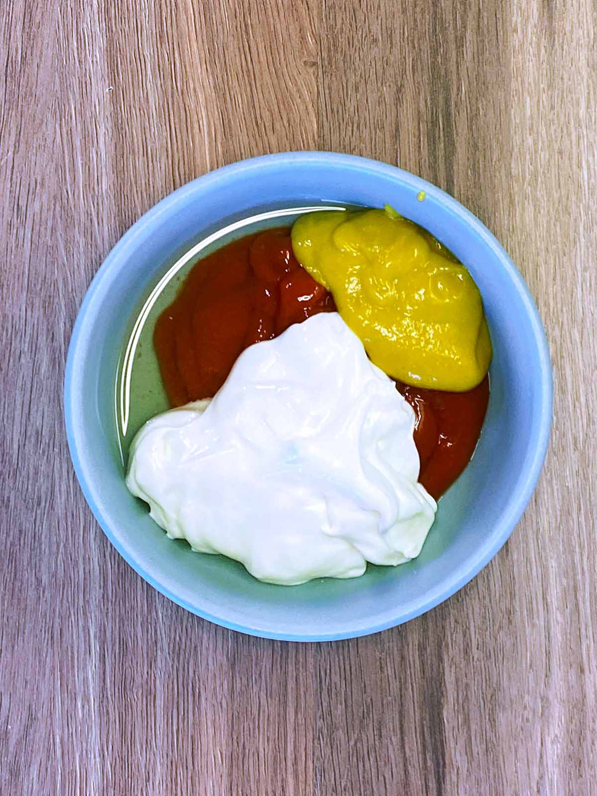 Mayonnaise, ketchup, mustard and pickle juice in a bowl.