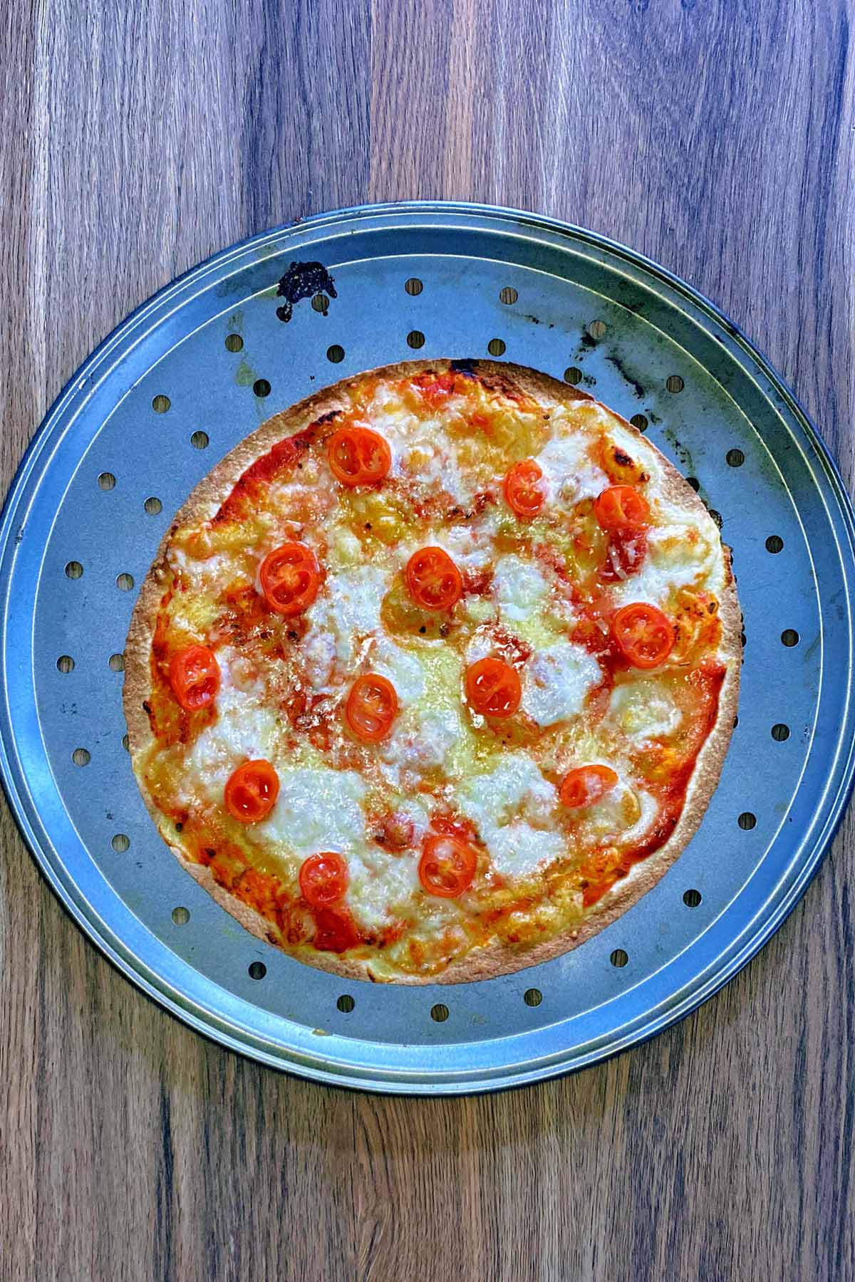 Cooked pizza on a pizza baking tray.