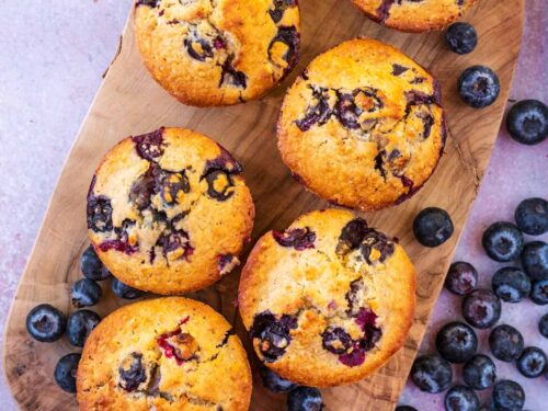 Six healthy blueberry muffins on a wooden serving board.