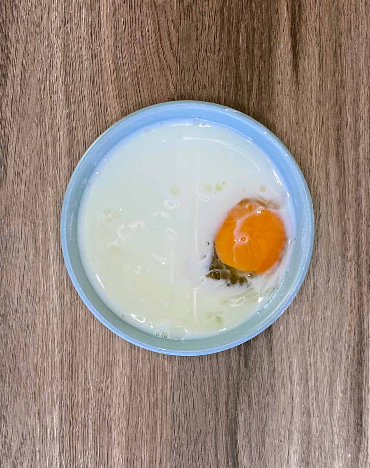 A bowl with milk and egg in it.