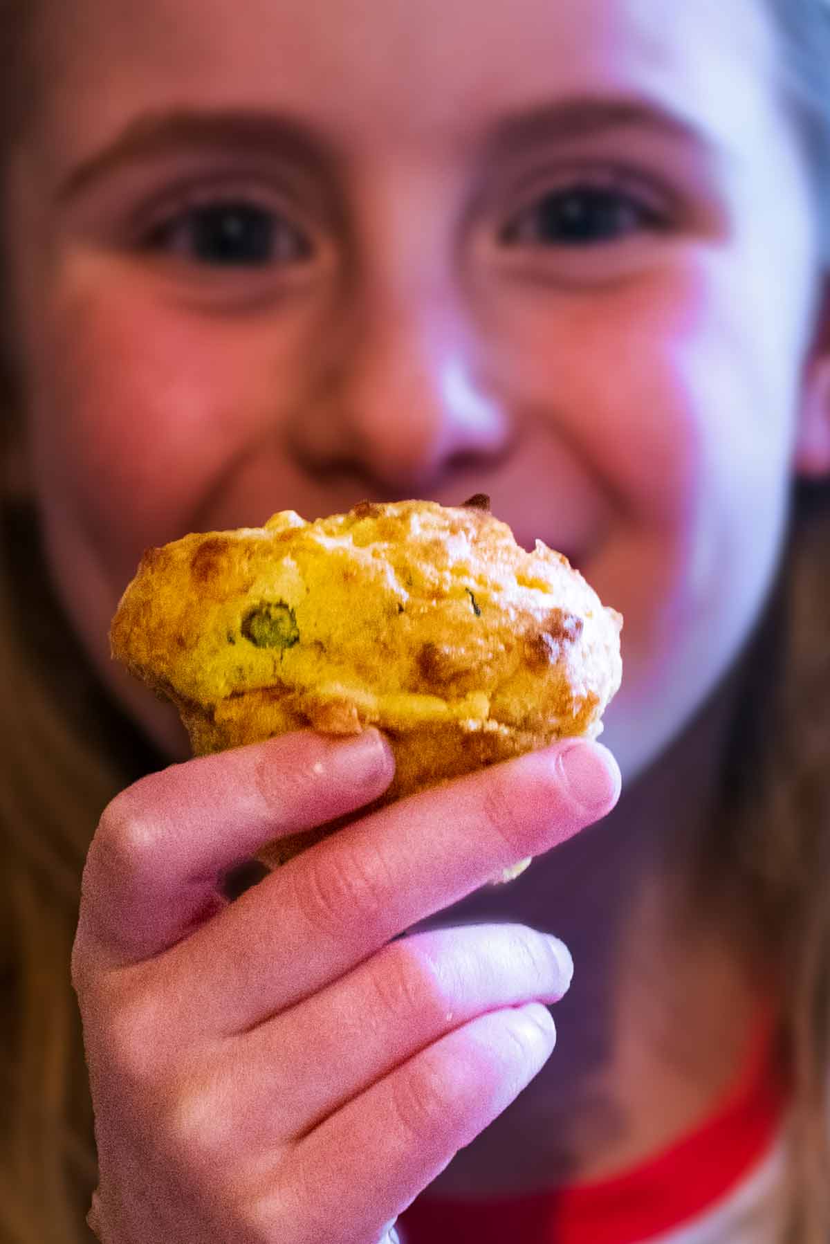 A child holding a muffin in front of her face.